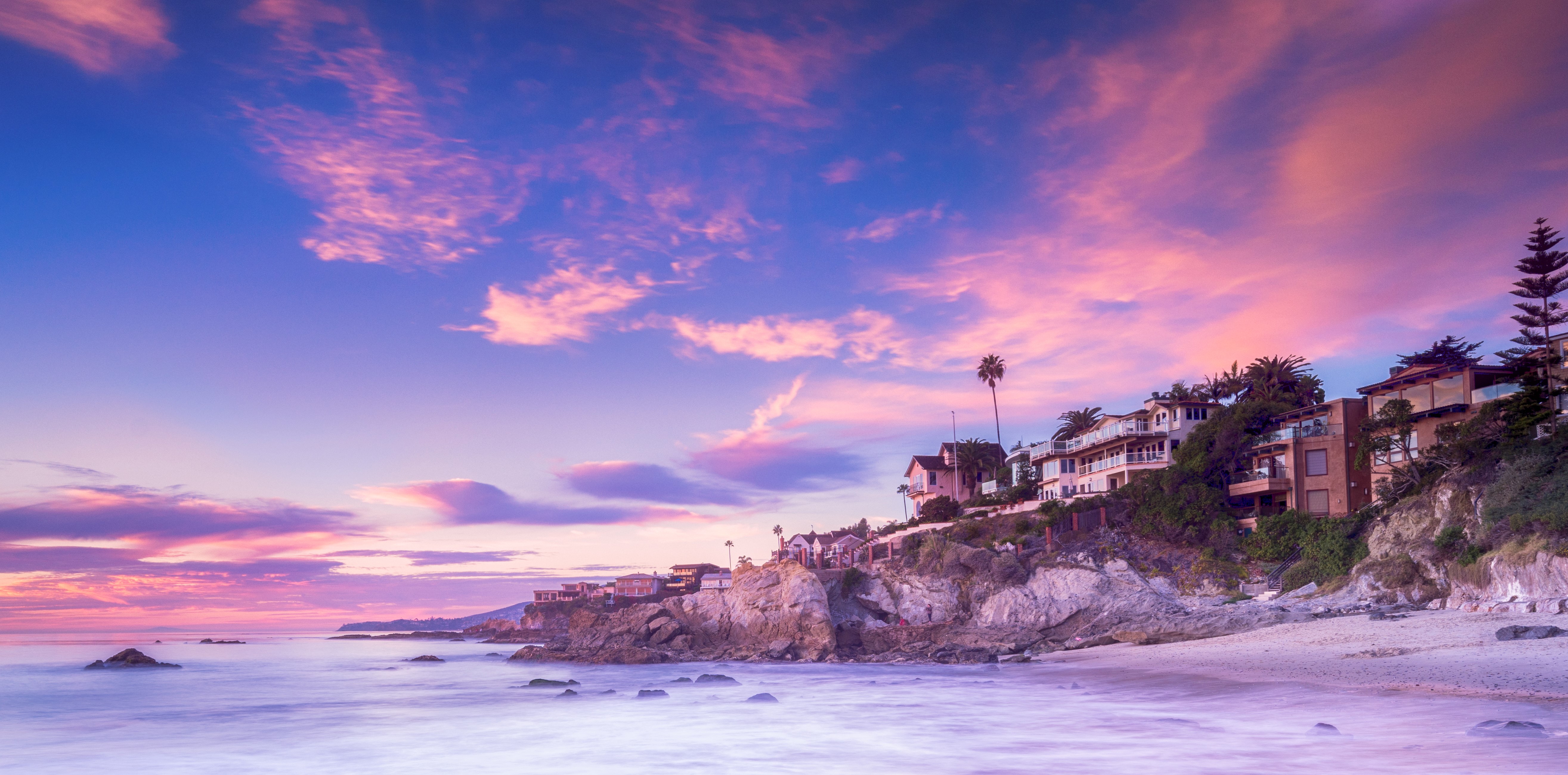 Houses on a cliff overlooking the ocean at sunset in Laguna Beach, California HD Wallpaper