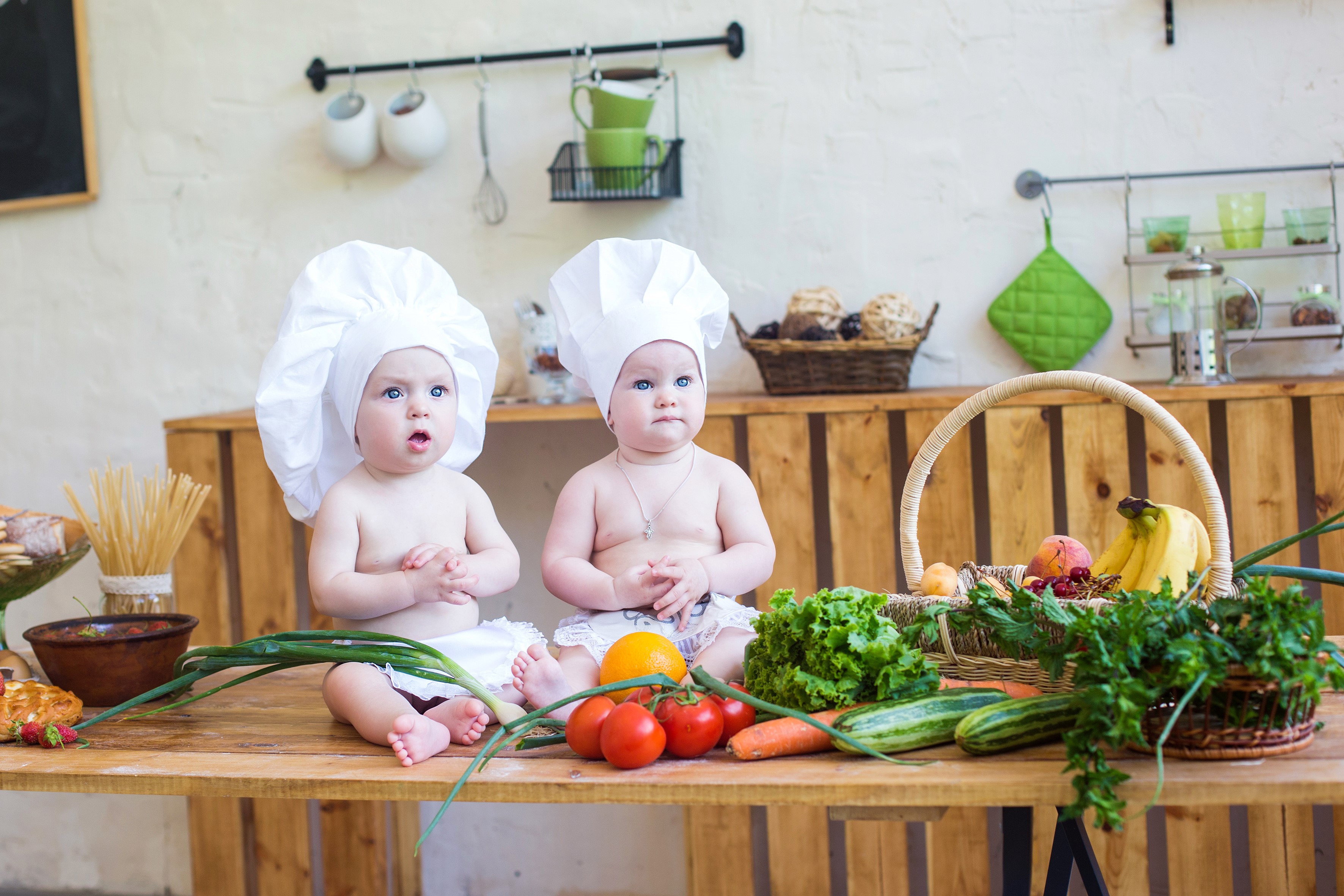 Two babies dressed as chefs in a kitchen with vegetables HD Wallpaper