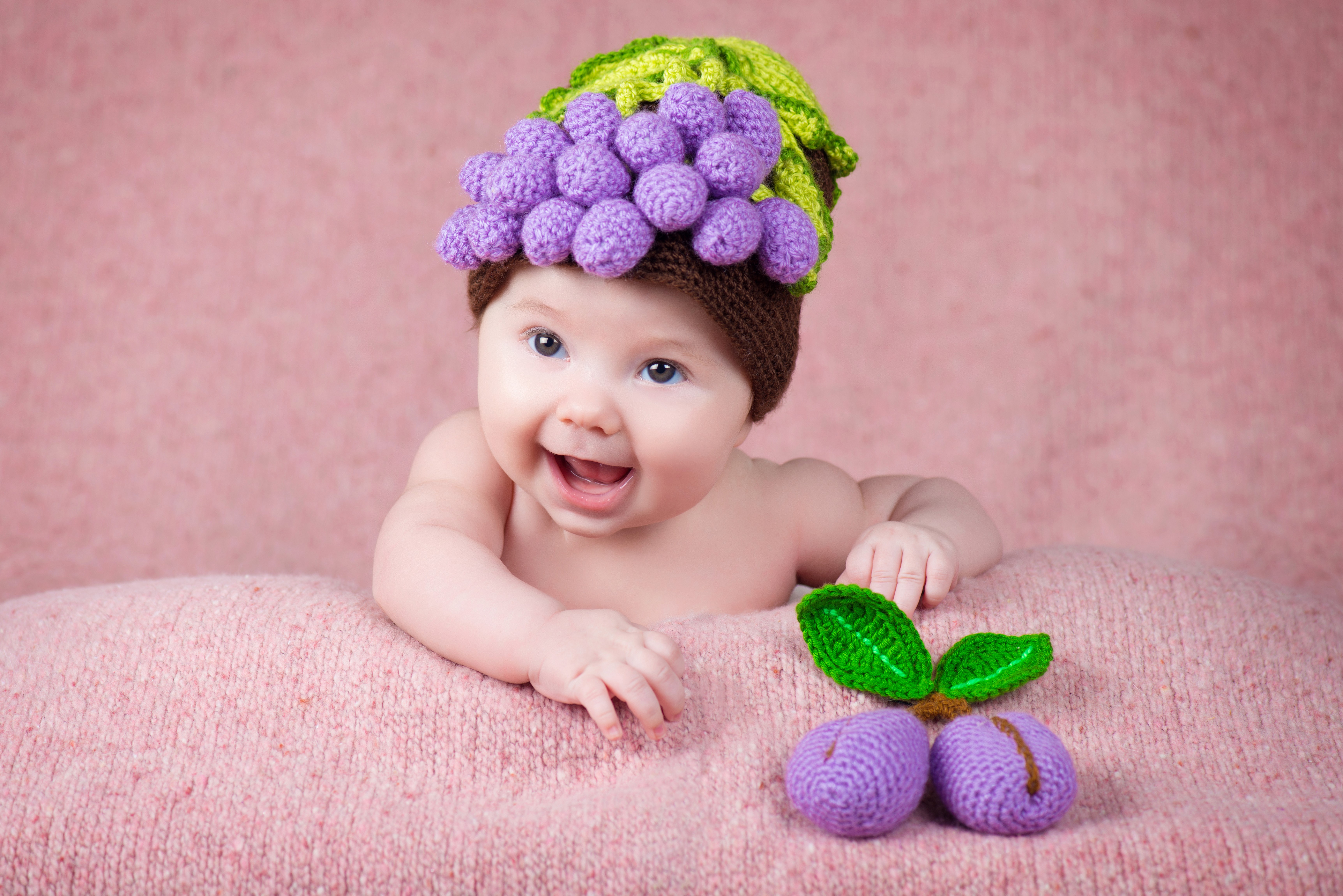 Baby wearing a grape-themed winter hat HD Wallpaper
