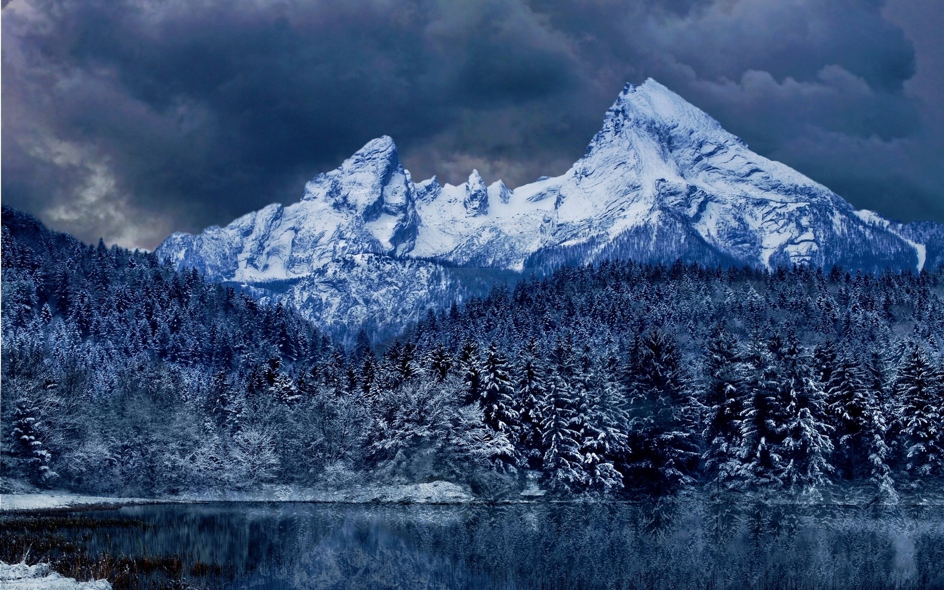Snow-covered mountains and forest reflected in a lake HD Wallpaper