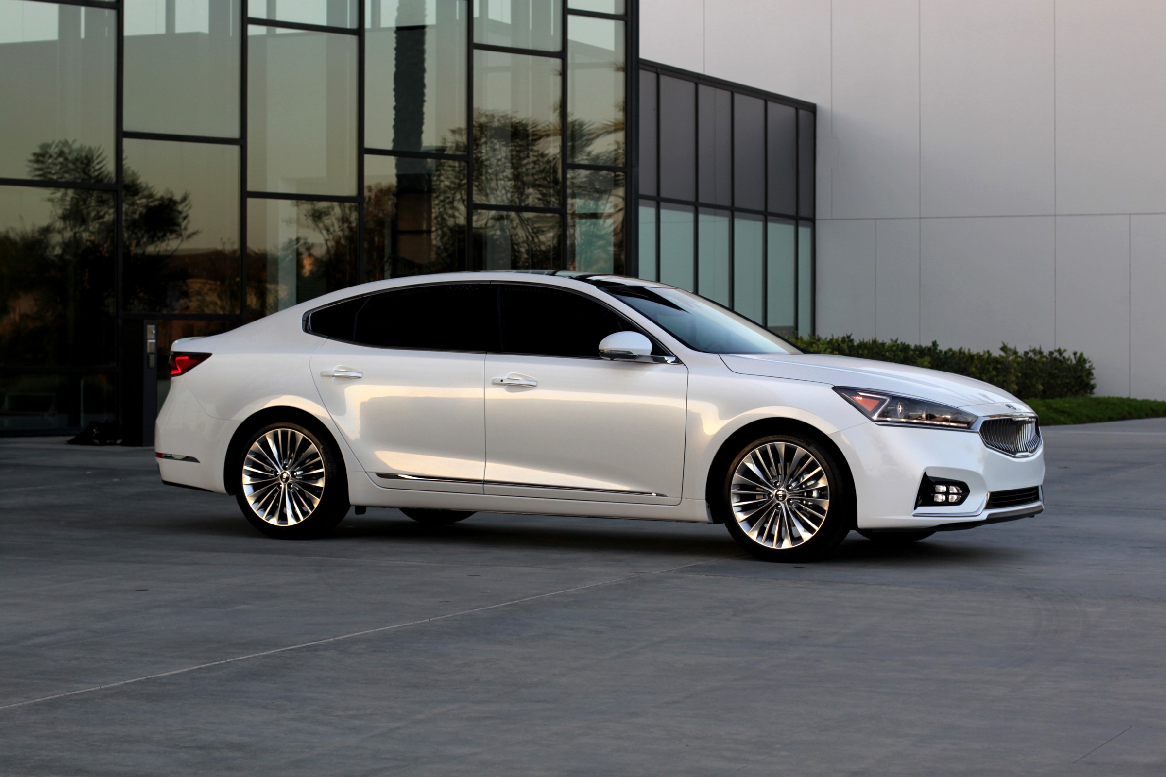 White 2017 Kia Cadenza sedan parked outside modern building HD Wallpaper