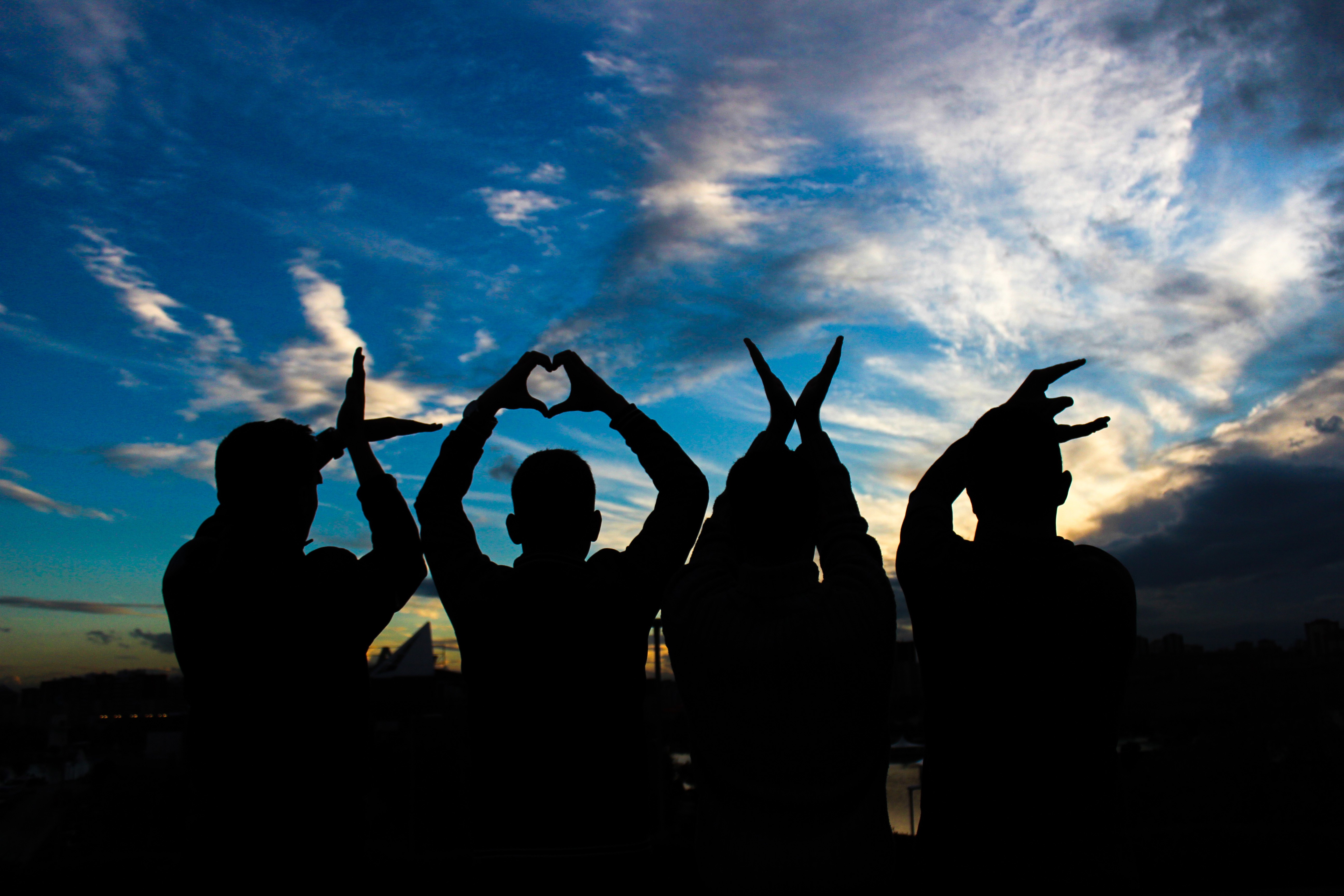 Four people silhouetted against a cloudy sky forming the word LOVE HD Wallpaper