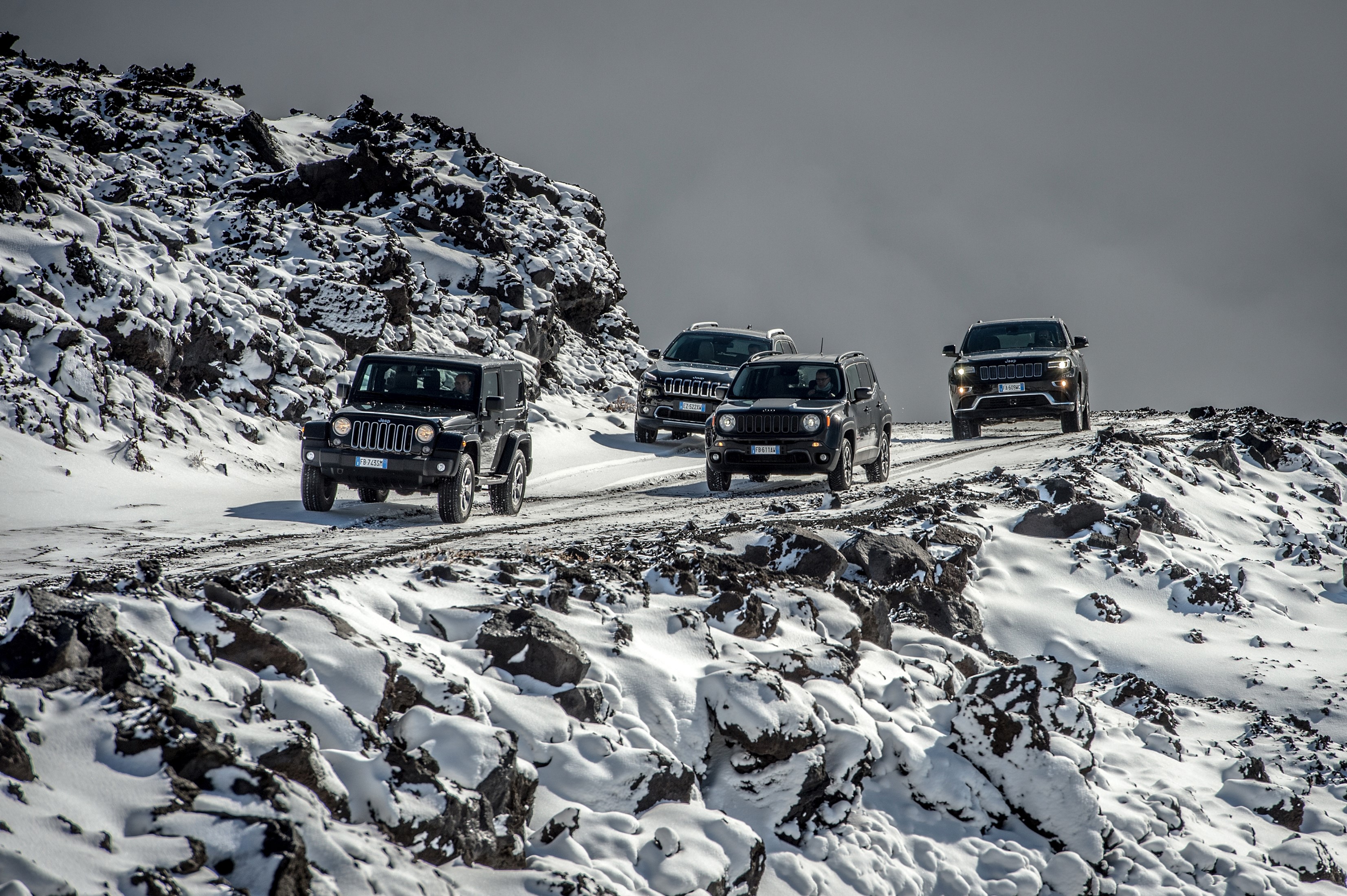 Jeeps driving on a snowy mountain road HD Wallpaper