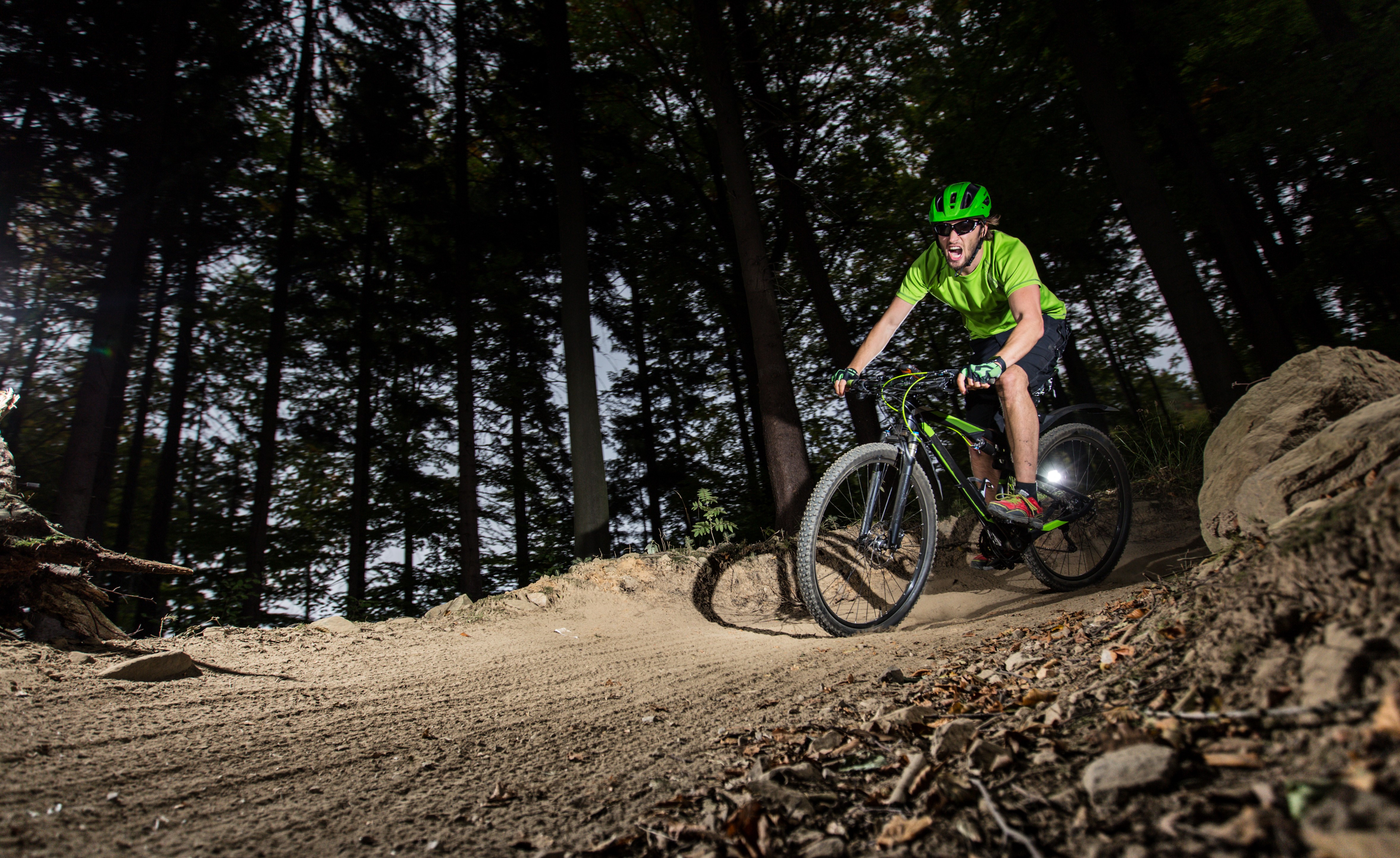 Man in helmet riding a bicycle in a forest HD Wallpaper