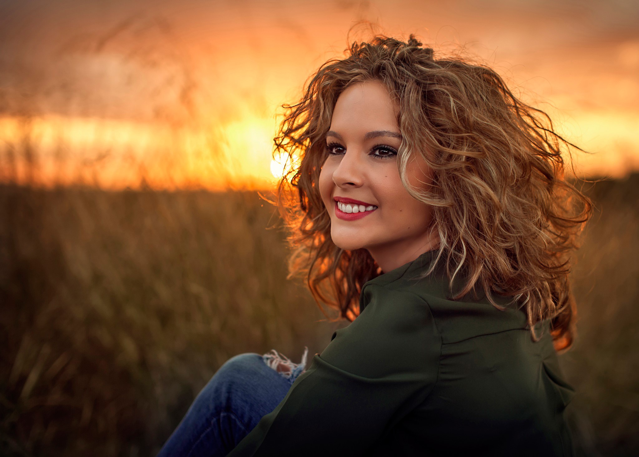 Woman with curly brown hair smiling at sunset HD Wallpaper
