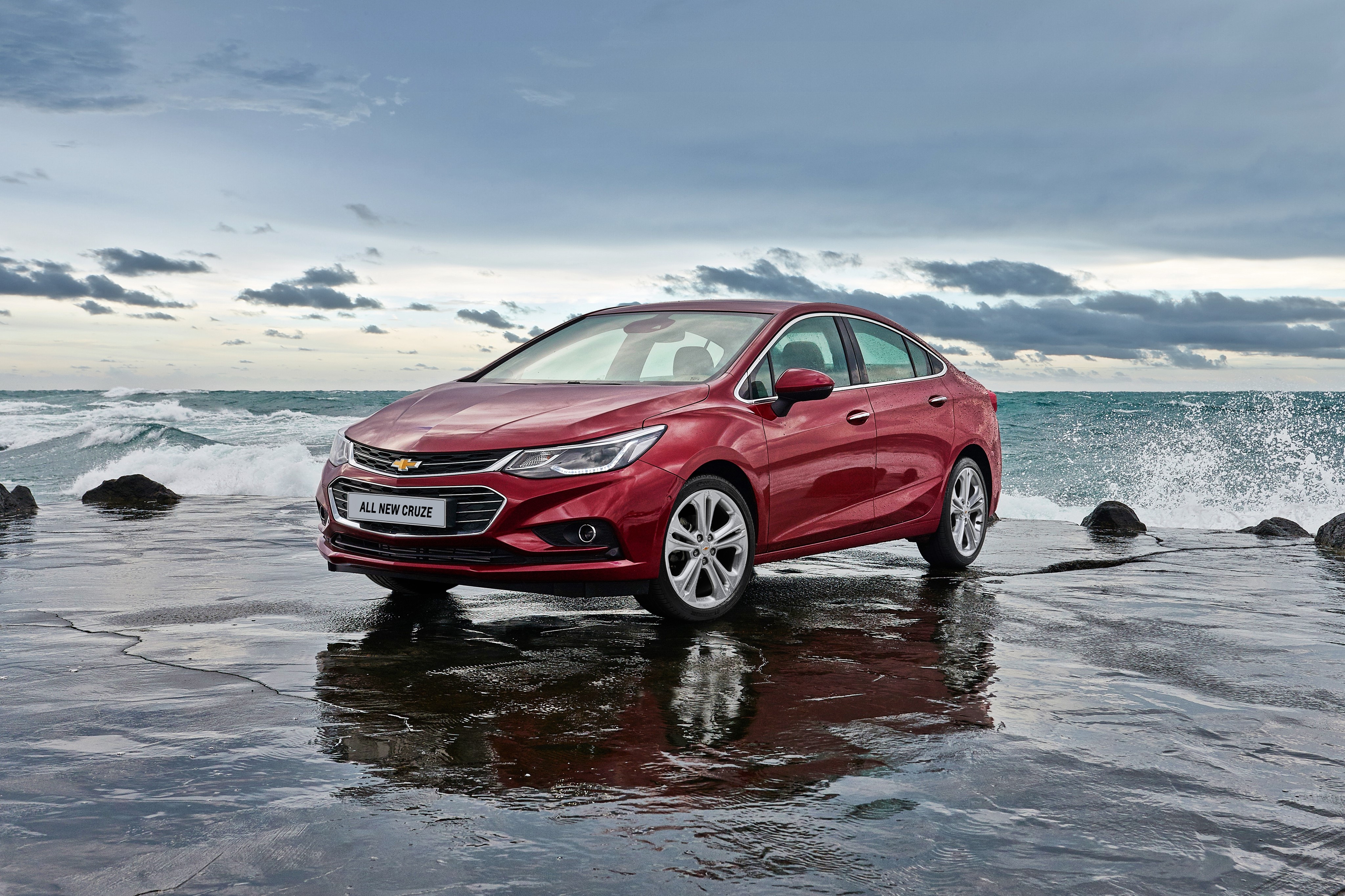 Red Chevrolet Cruze parked by the ocean HD Wallpaper