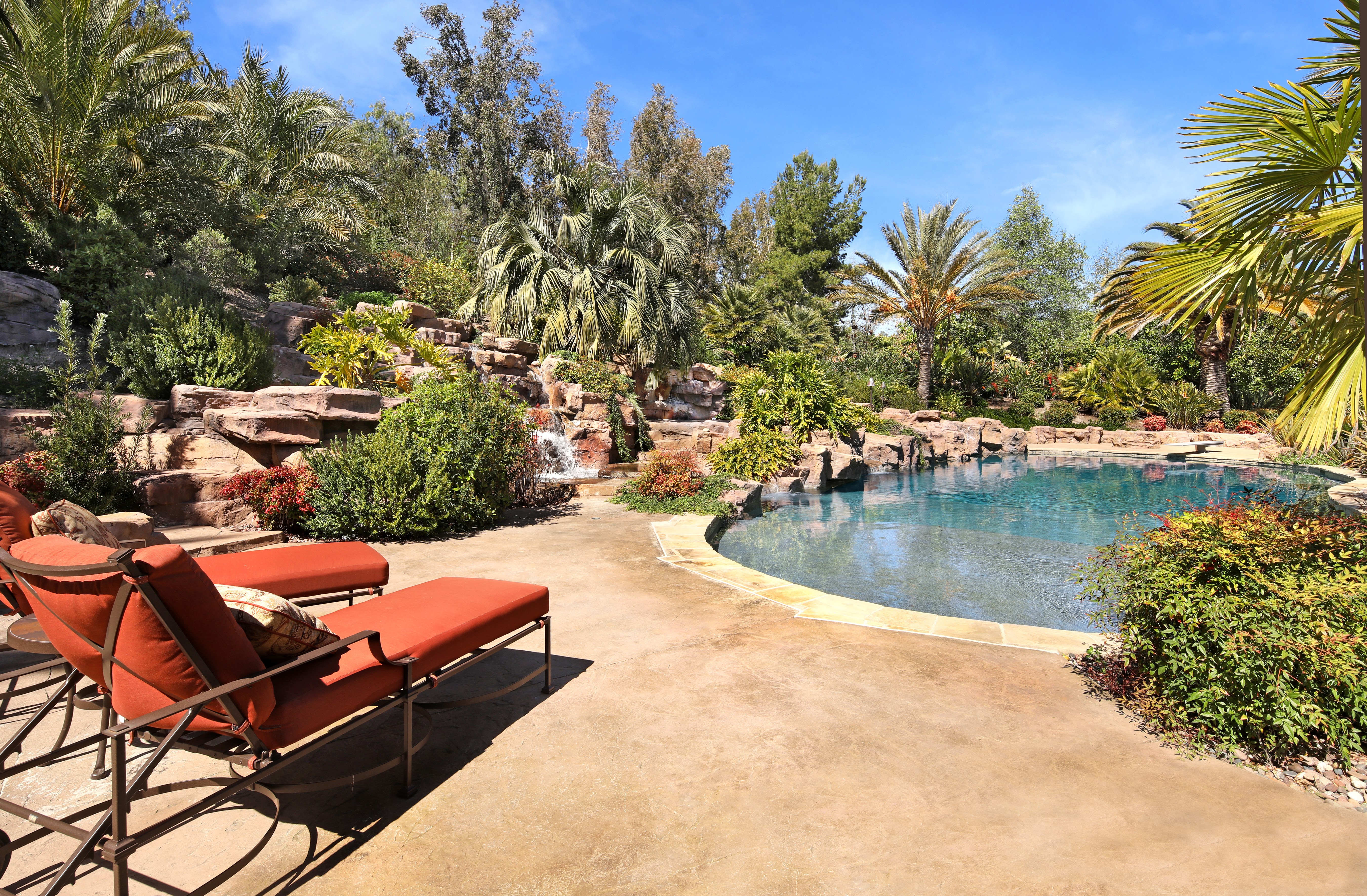 Resort pool with chaise lounges and rock waterfall HD Wallpaper