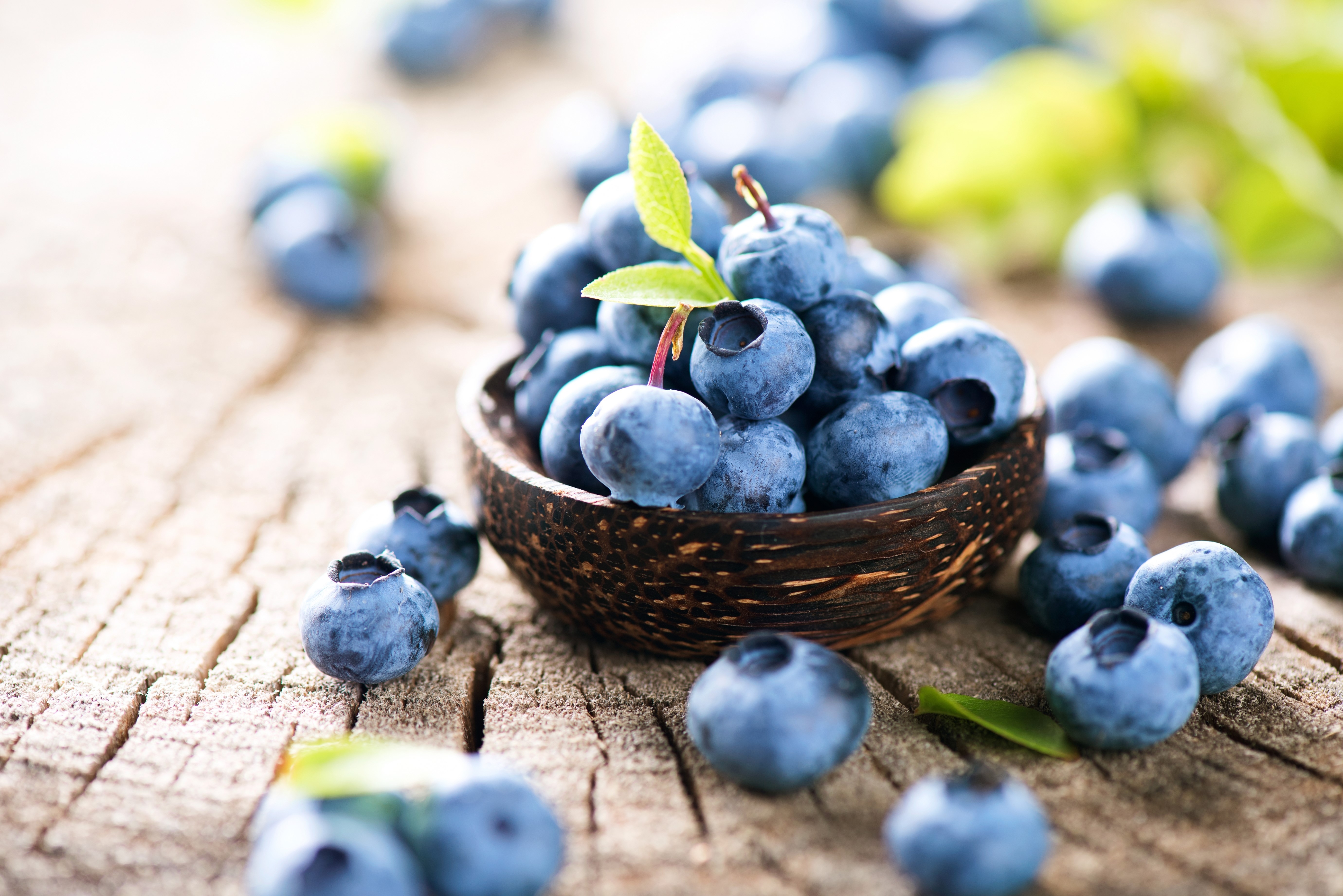 Blueberries in a bowl on a wooden surface HD Wallpaper