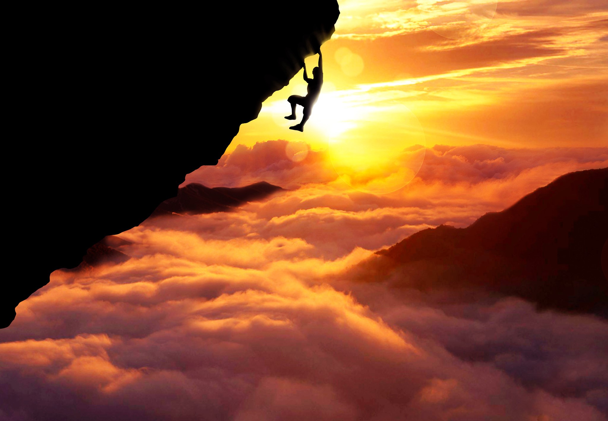 Silhouette of a climber hanging from a cliff at sunset above clouds HD Wallpaper