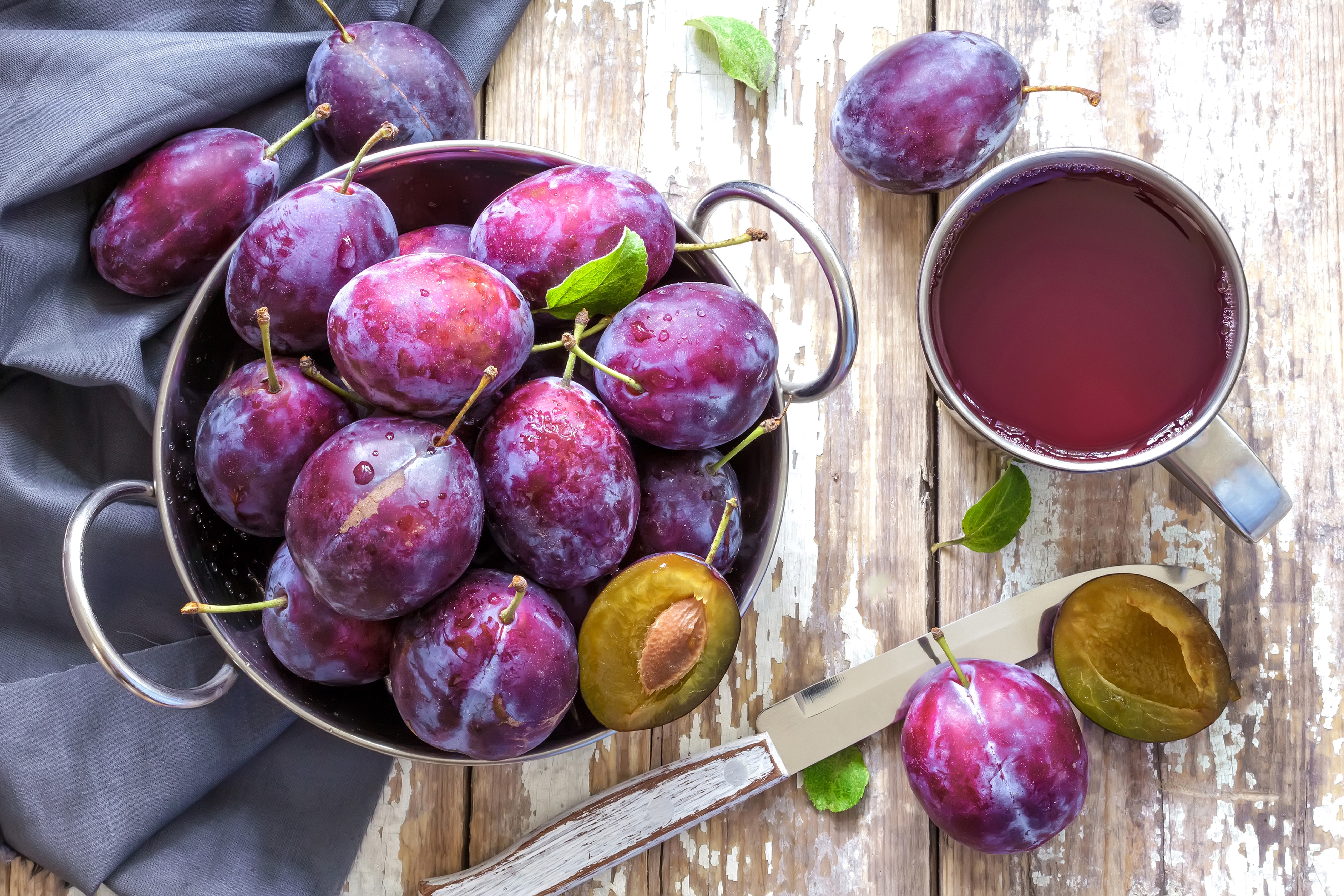 Plums and plum juice on a wooden table HD Wallpaper