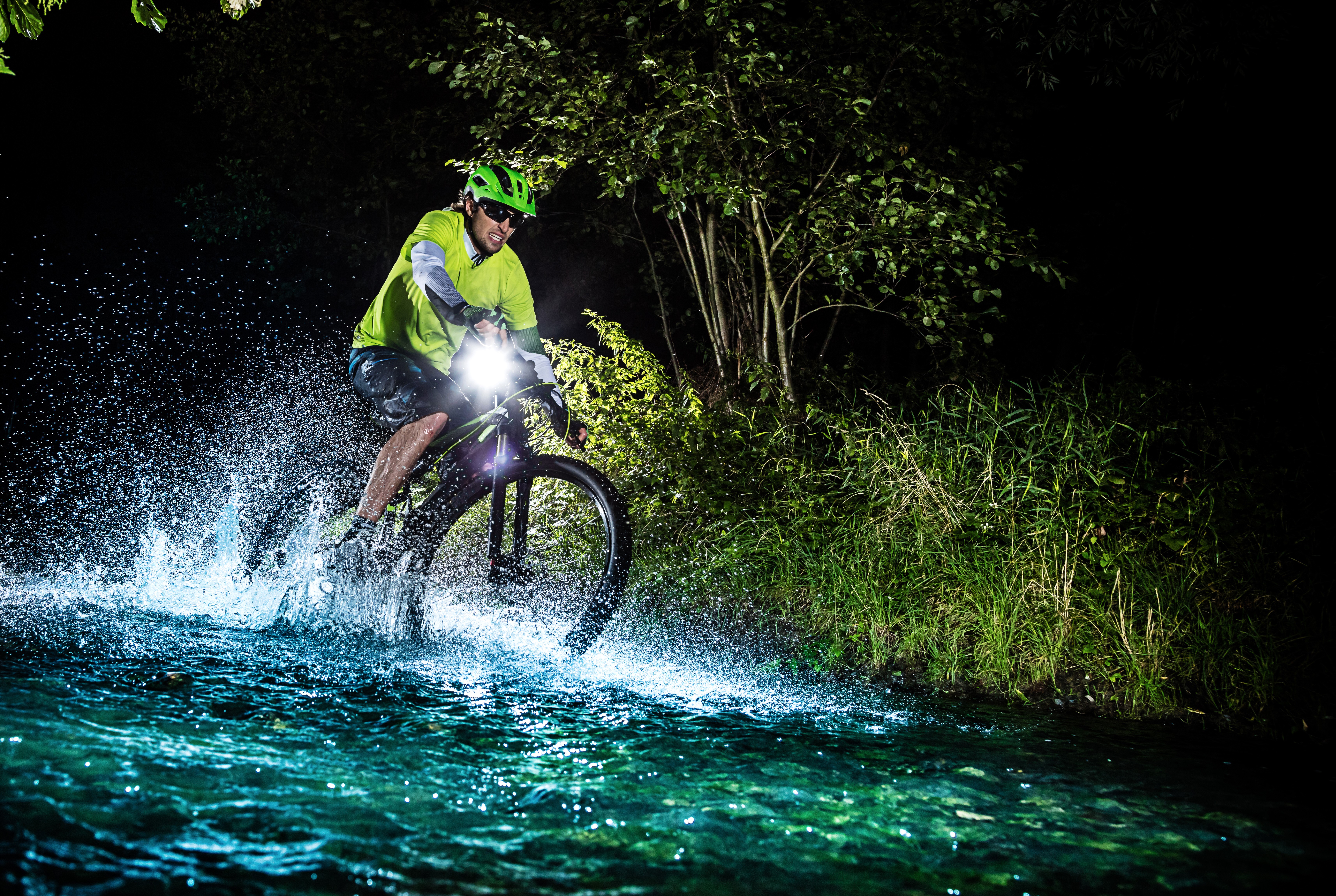 Man riding a bicycle through water at night HD Wallpaper