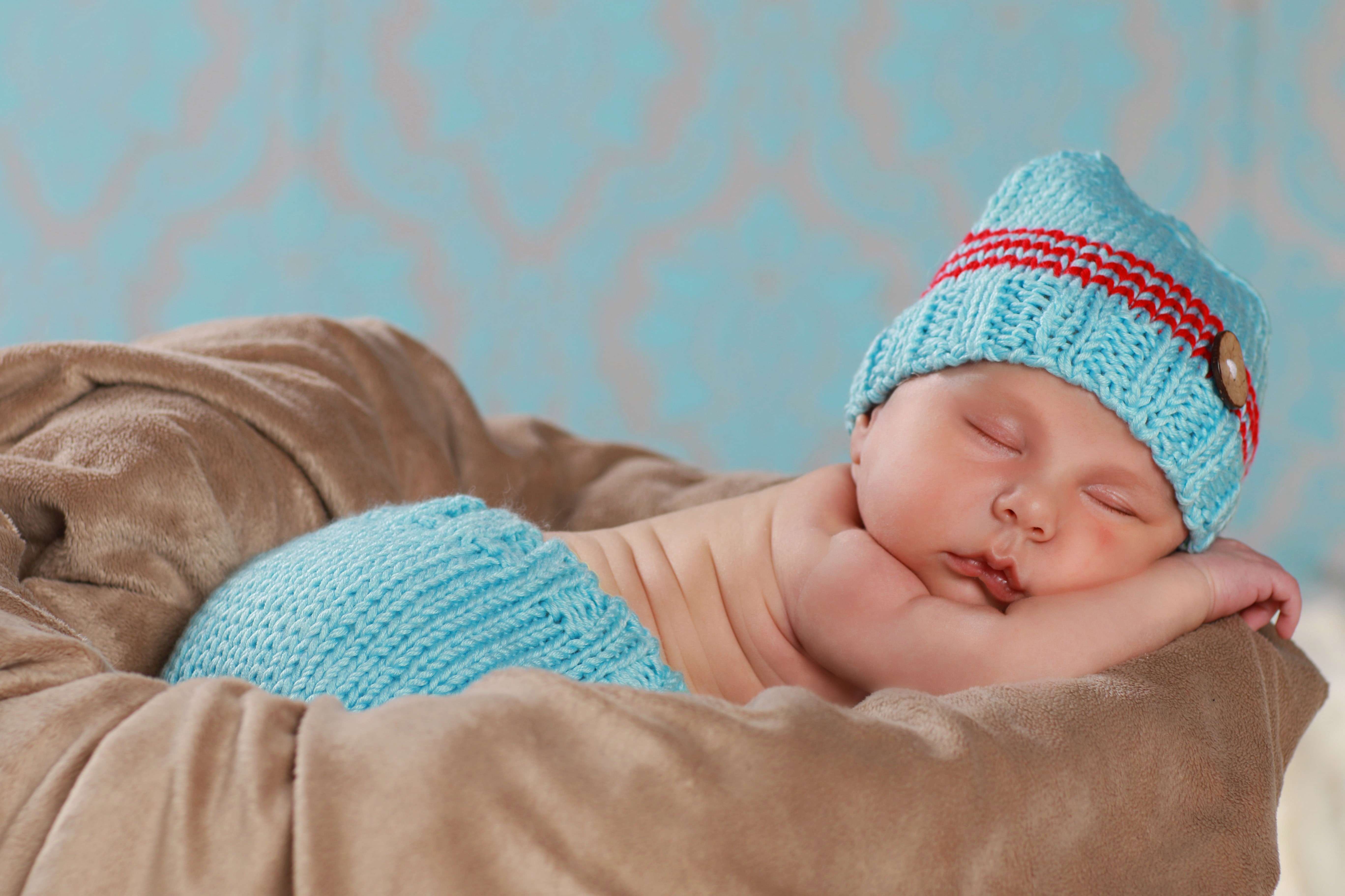 Newborn baby sleeping in a basket wearing a winter hat HD Wallpaper