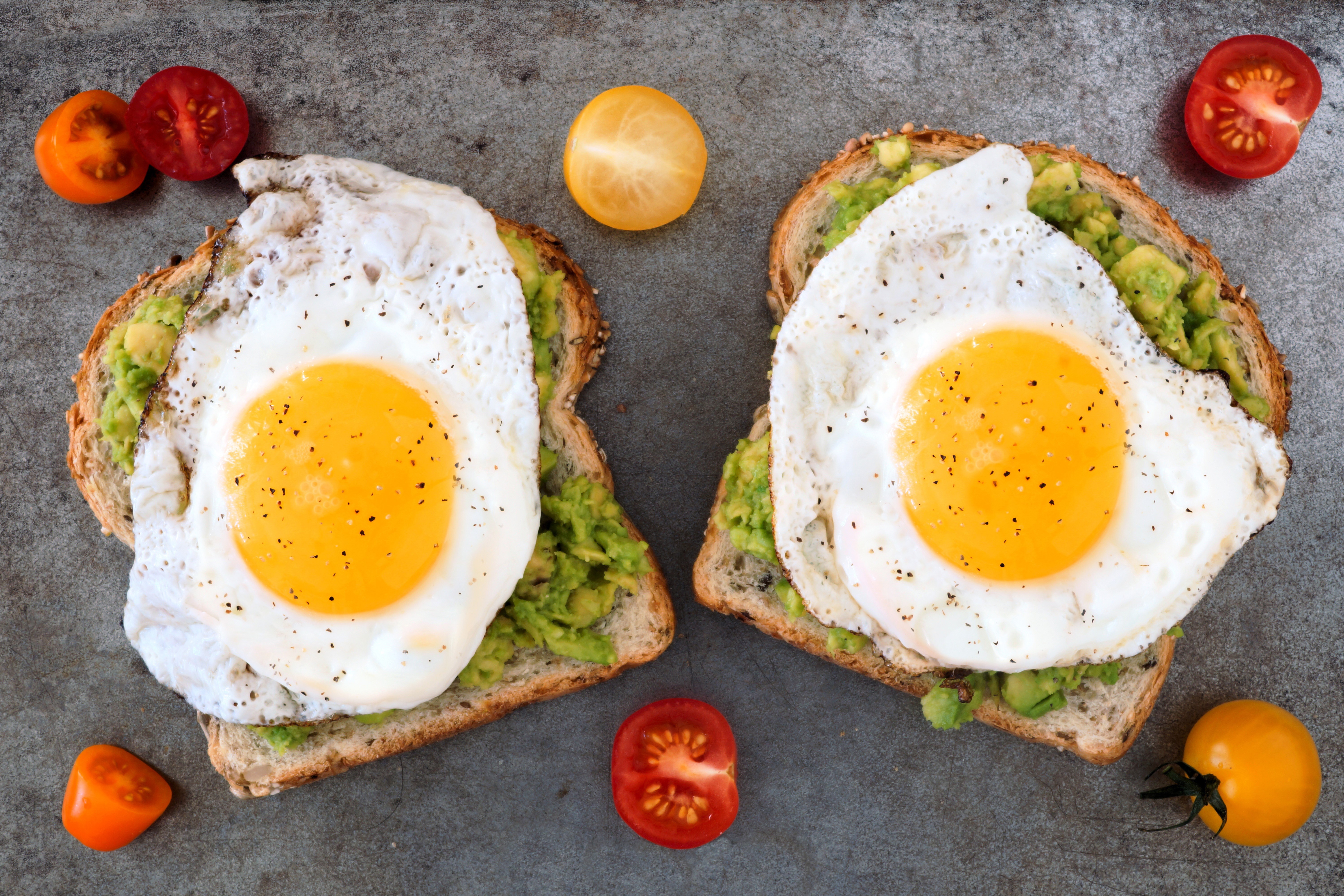 Two avocado toasts with fried eggs and tomatoes HD Wallpaper