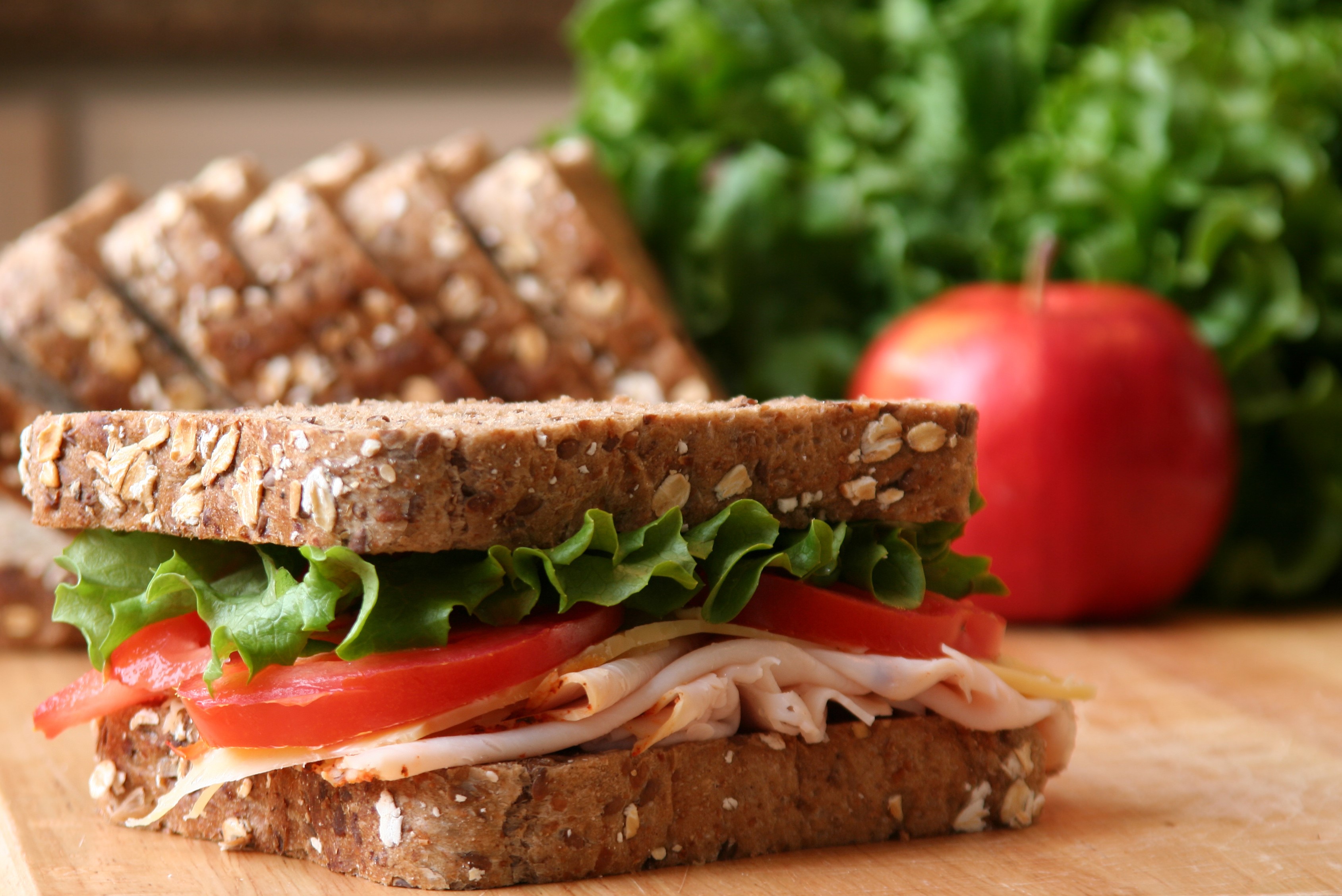 Turkey sandwich with lettuce, tomato, and cheese on whole grain bread HD Wallpaper