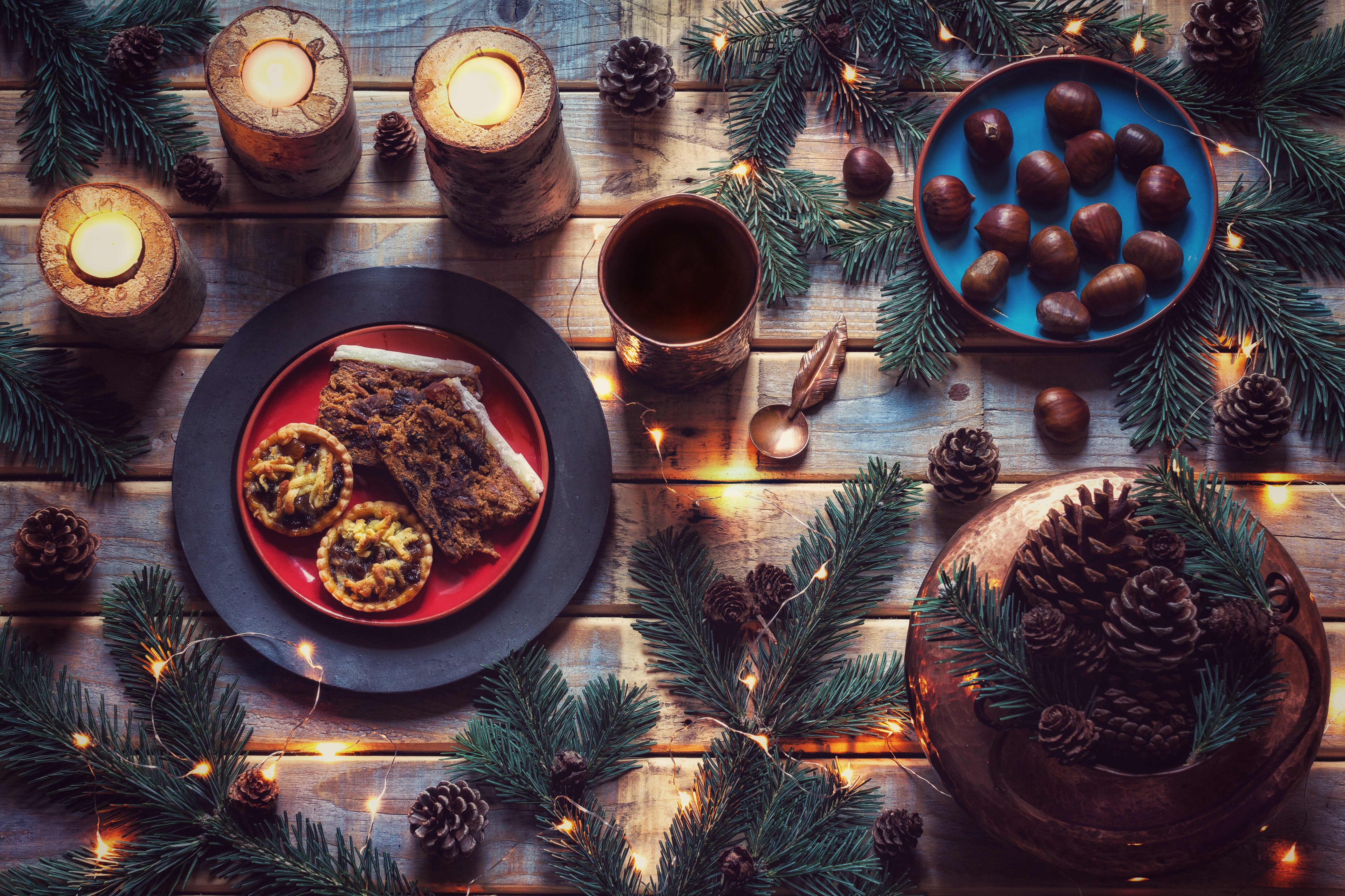 Christmas pastries and chestnuts on wooden table with candles and fir branches HD Wallpaper