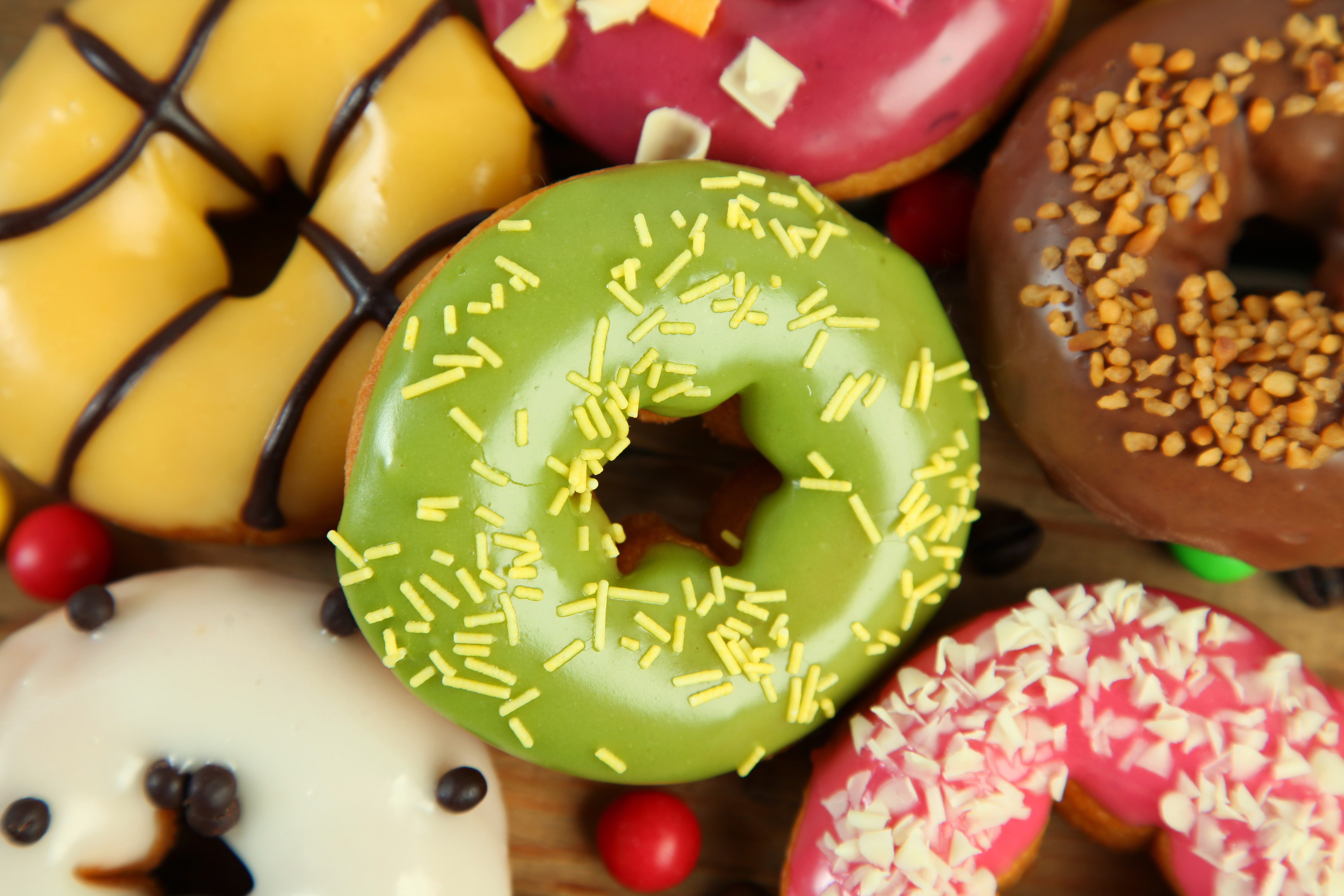 Assortment of colorful donuts with various toppings HD Wallpaper