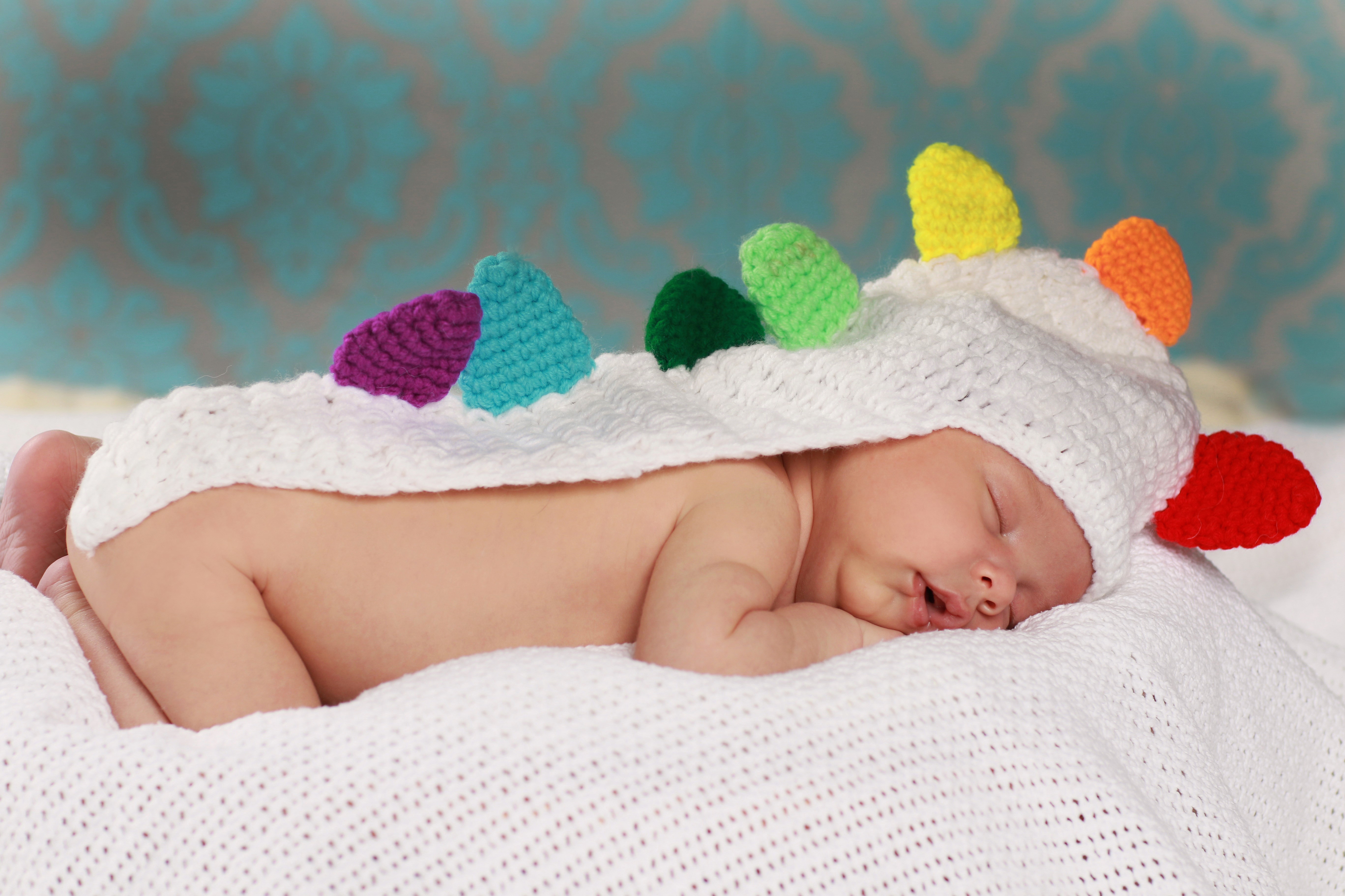 Baby sleeping in a colorful crochet unicorn costume HD Wallpaper