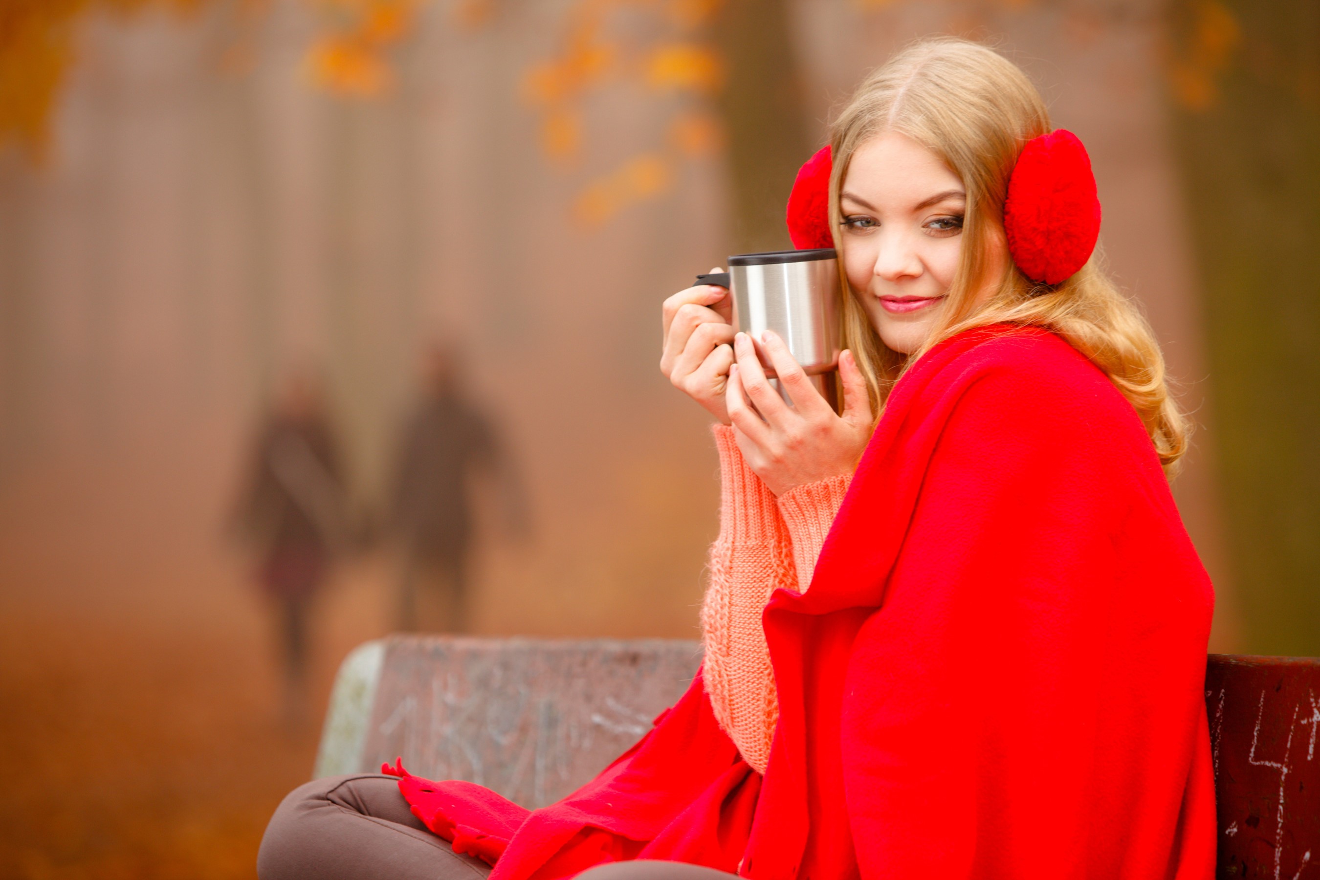 Woman in earmuffs holding a mug in autumn park HD Wallpaper
