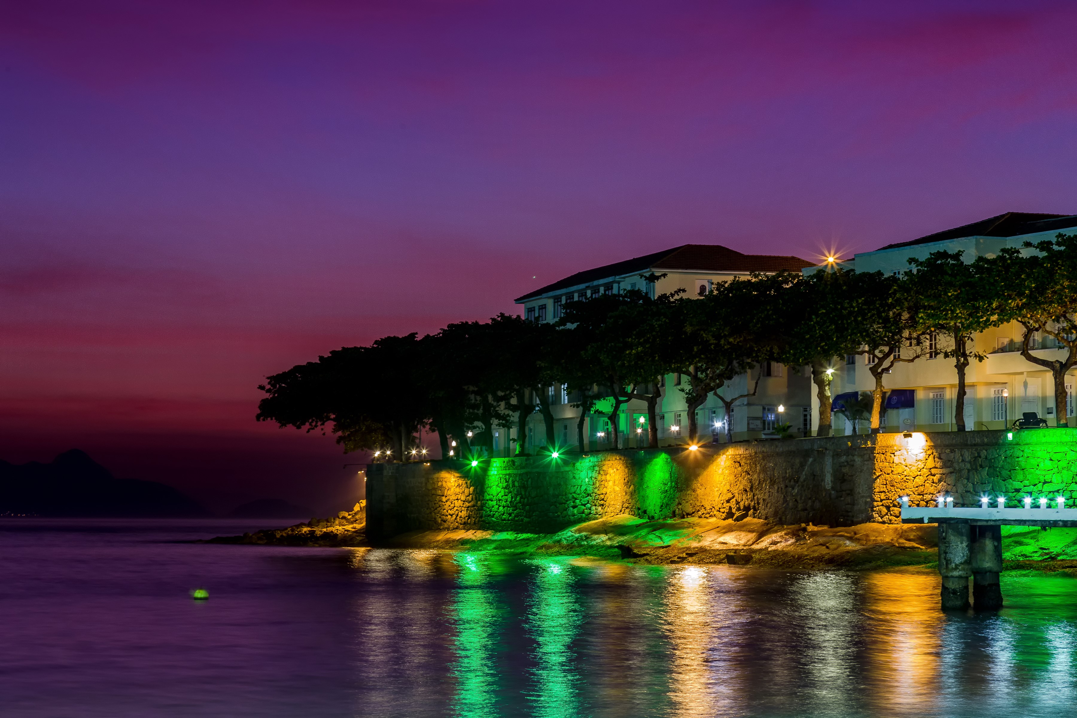 Buildings and trees illuminated at night by the sea in Rio de Janeiro HD Wallpaper