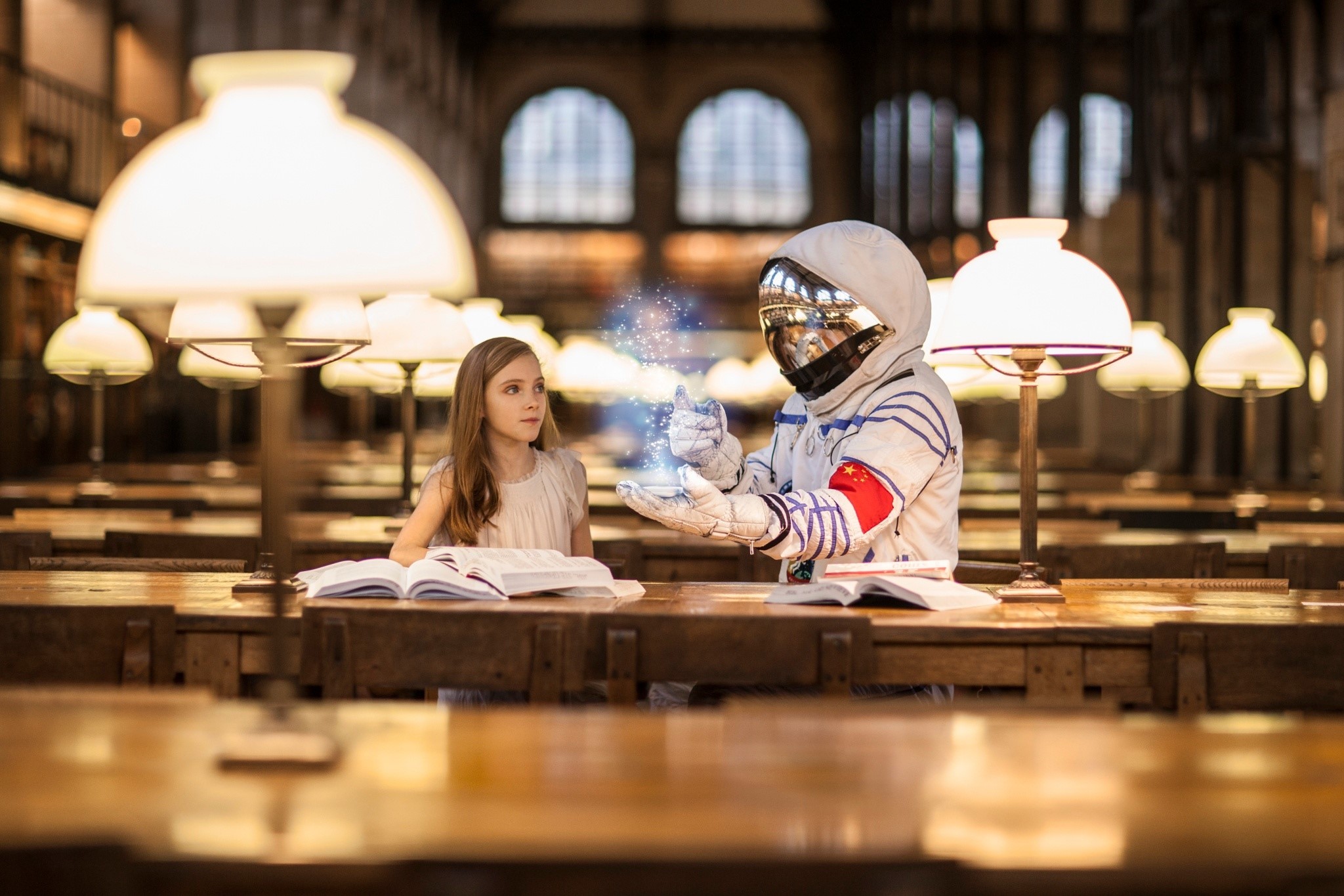 Astronaut showing magic to a girl in a library HD Wallpaper