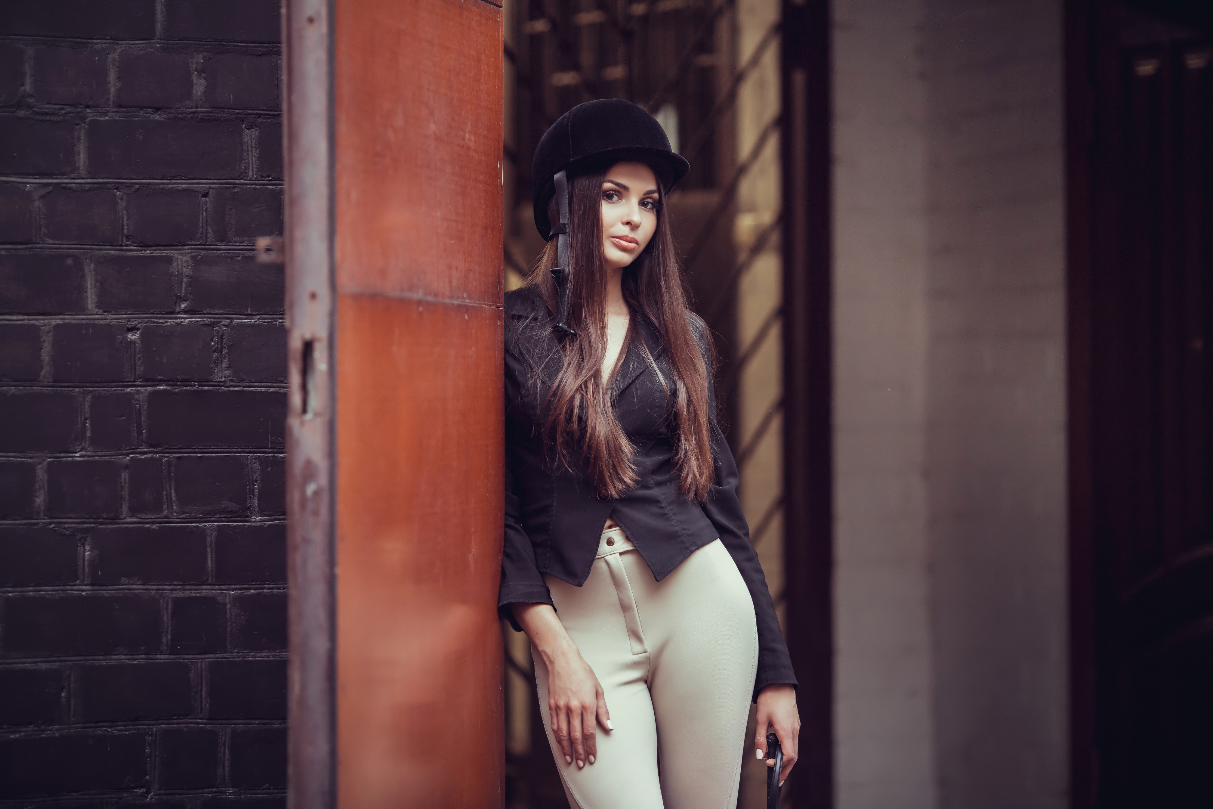 Woman in equestrian uniform leaning against a door HD Wallpaper