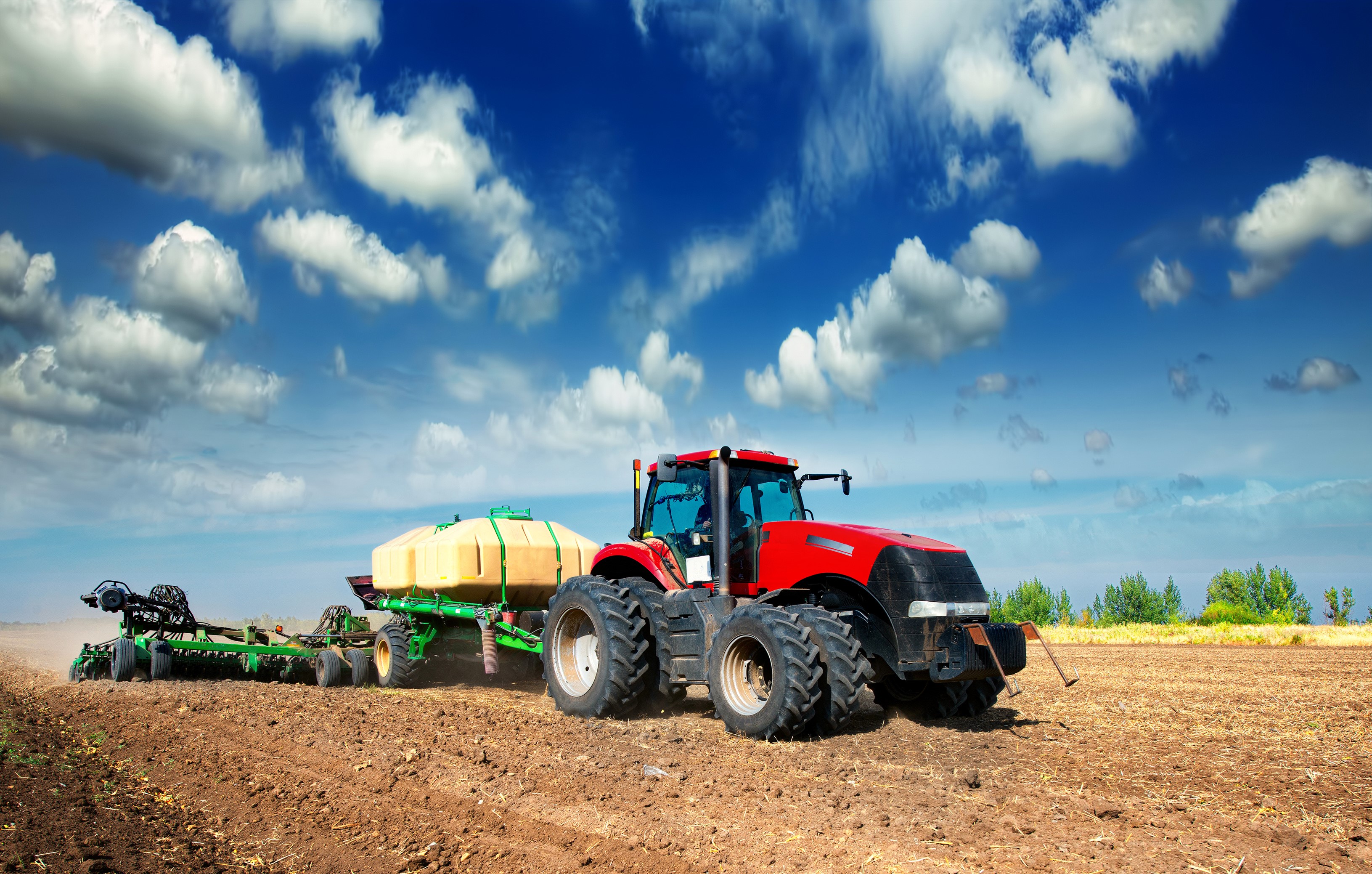 Red tractor plowing a field with a planter HD Wallpaper