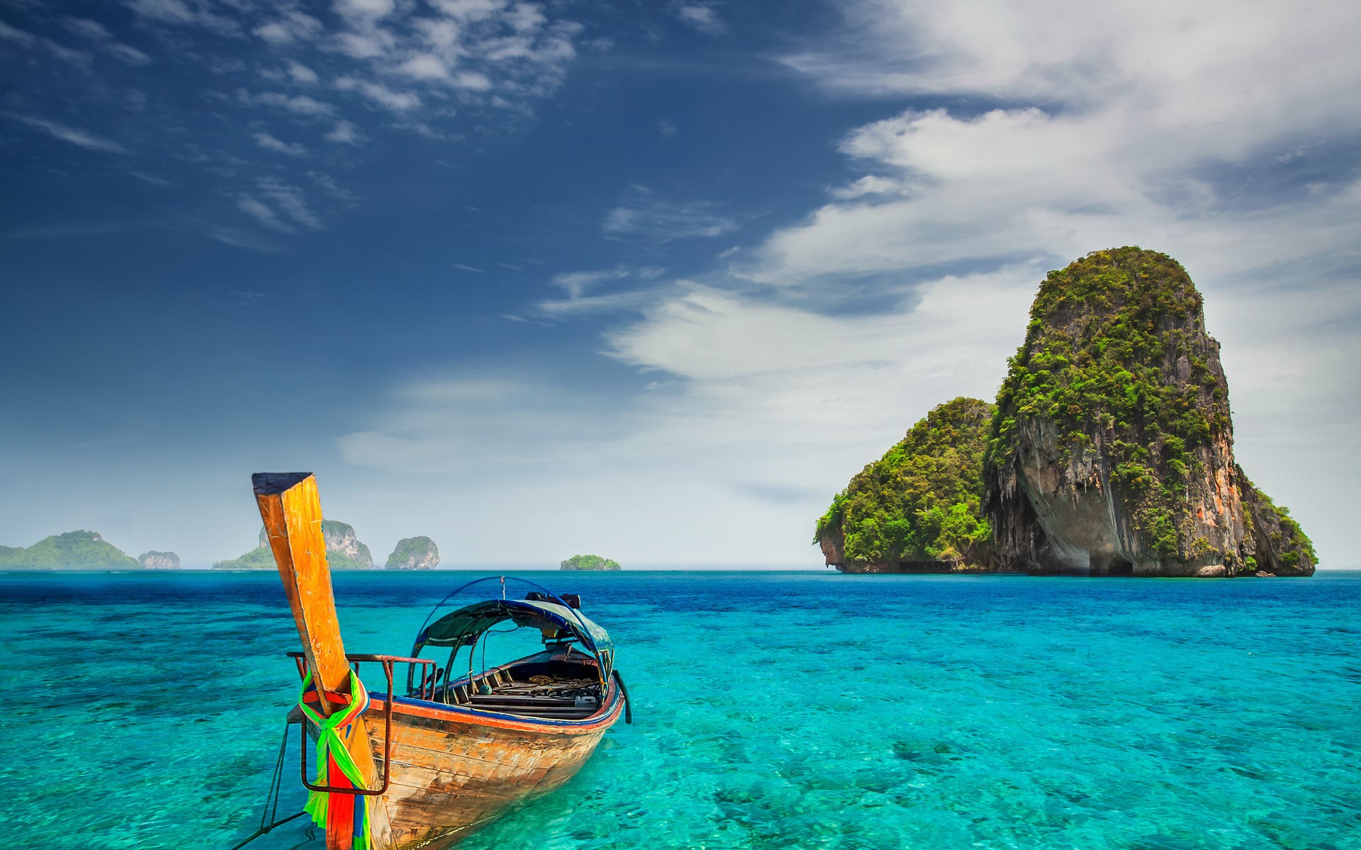 Longtail boat in turquoise water near limestone islands HD Wallpaper