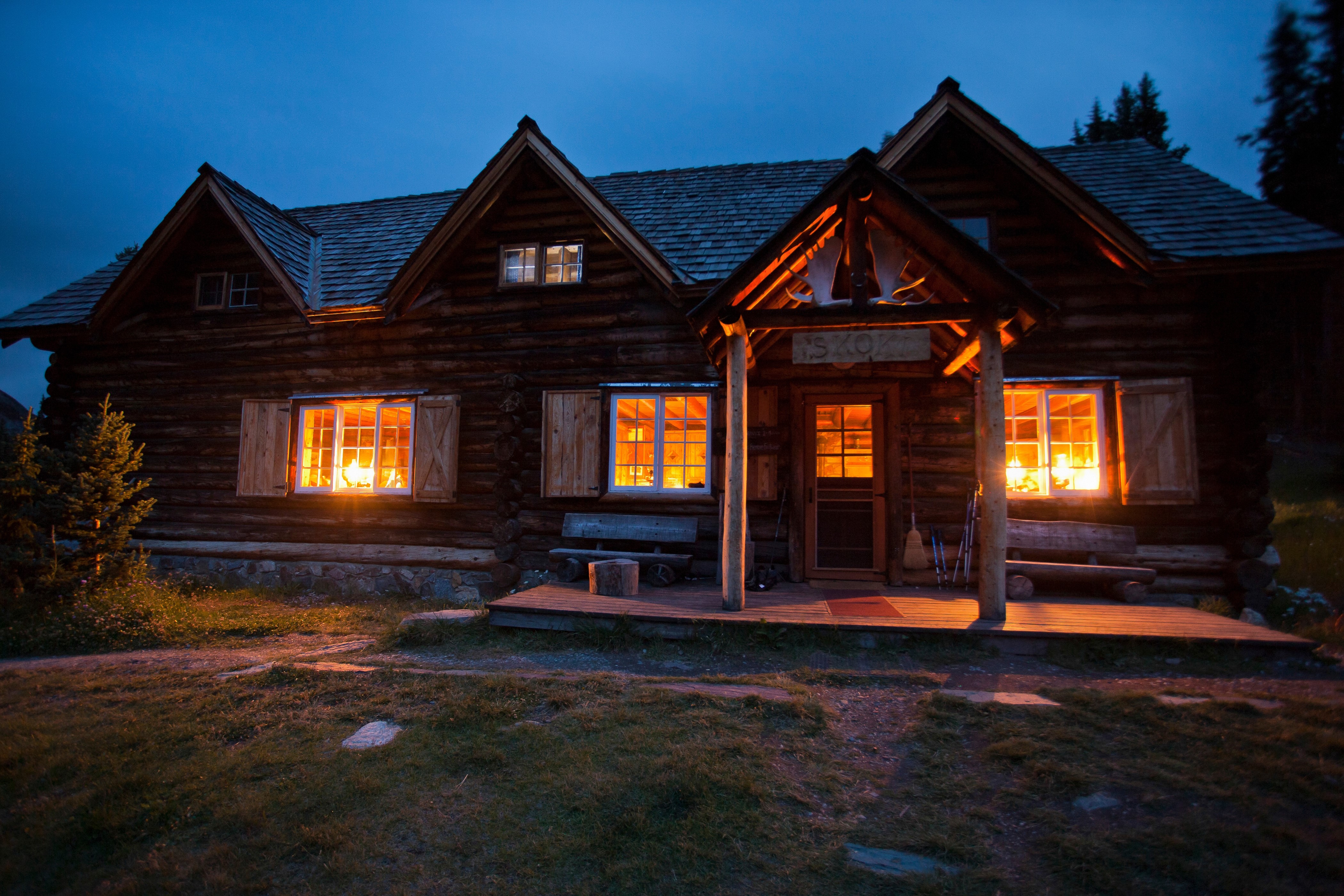 Log cabin at dusk with glowing windows HD Wallpaper