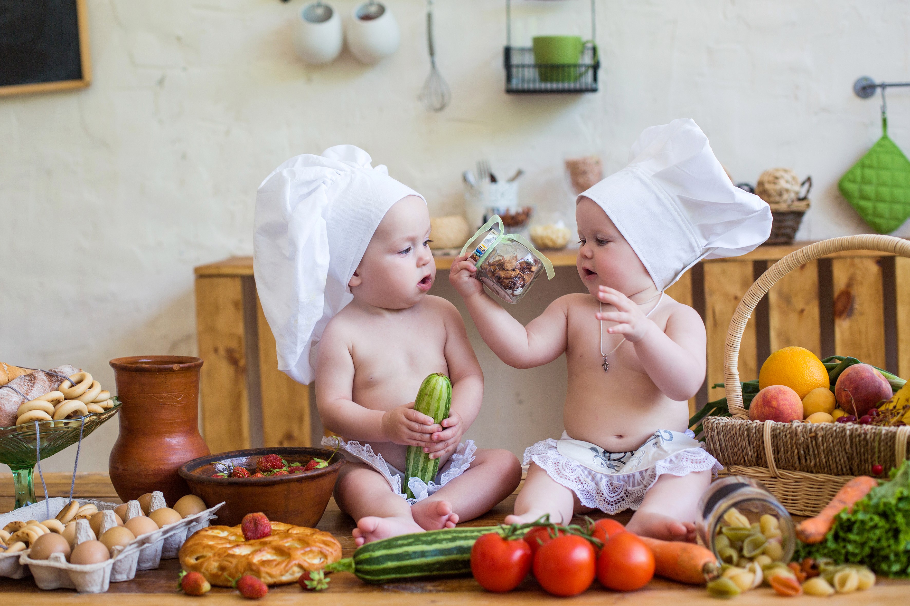 Two babies dressed as chefs in a kitchen with food HD Wallpaper