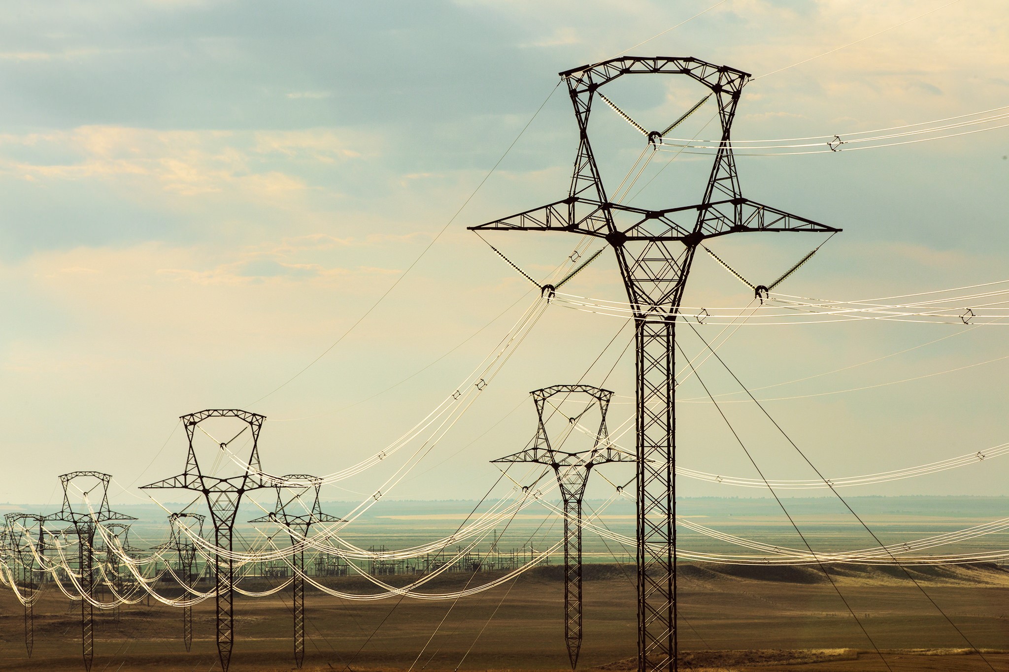 Power lines stretching across a vast landscape HD Wallpaper