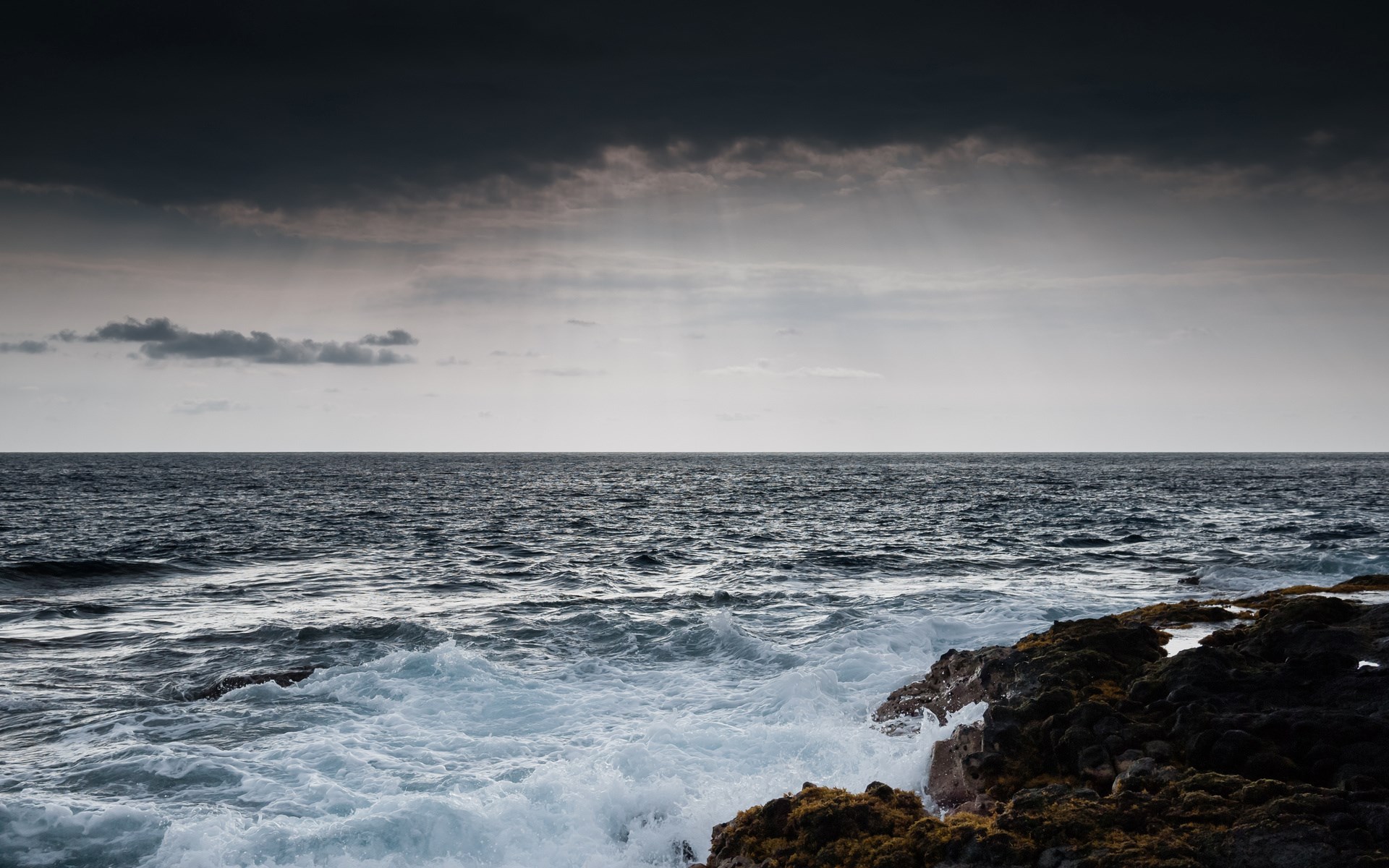 Waves crashing on rocky shore under stormy sky HD Wallpaper