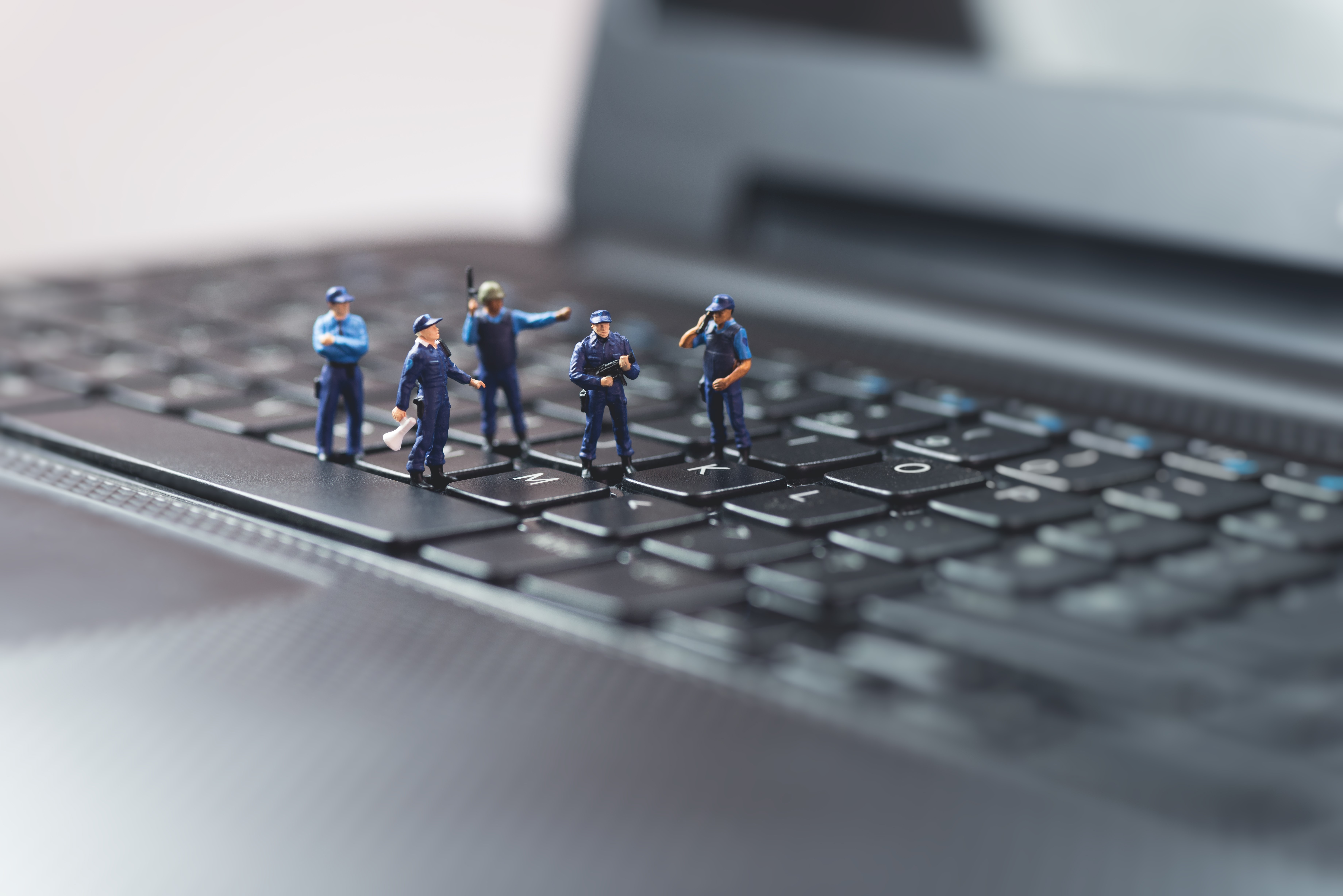 Miniature police figures on a laptop keyboard HD Wallpaper
