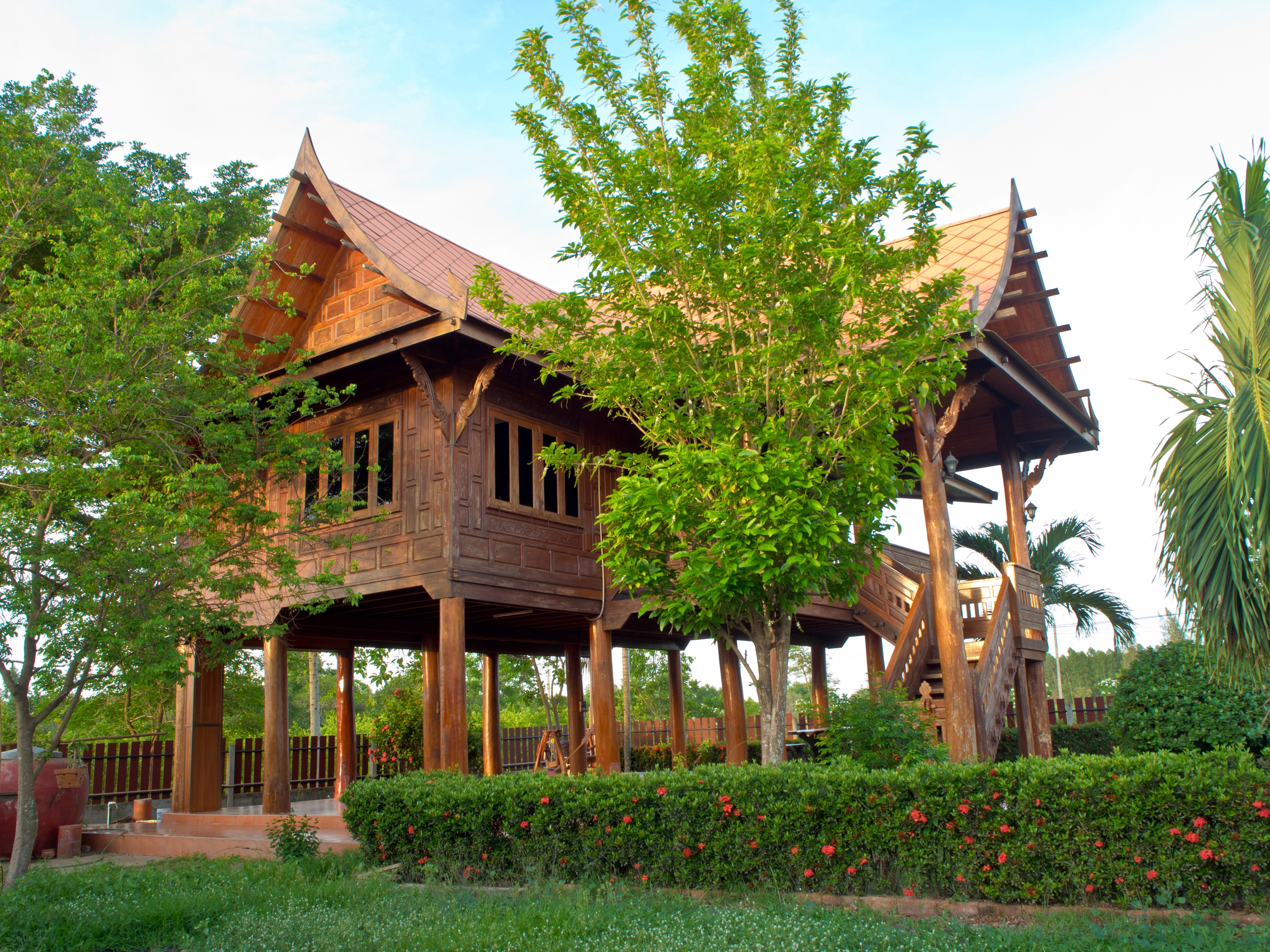 Thai style wooden house on stilts with trees and shrubs HD Wallpaper