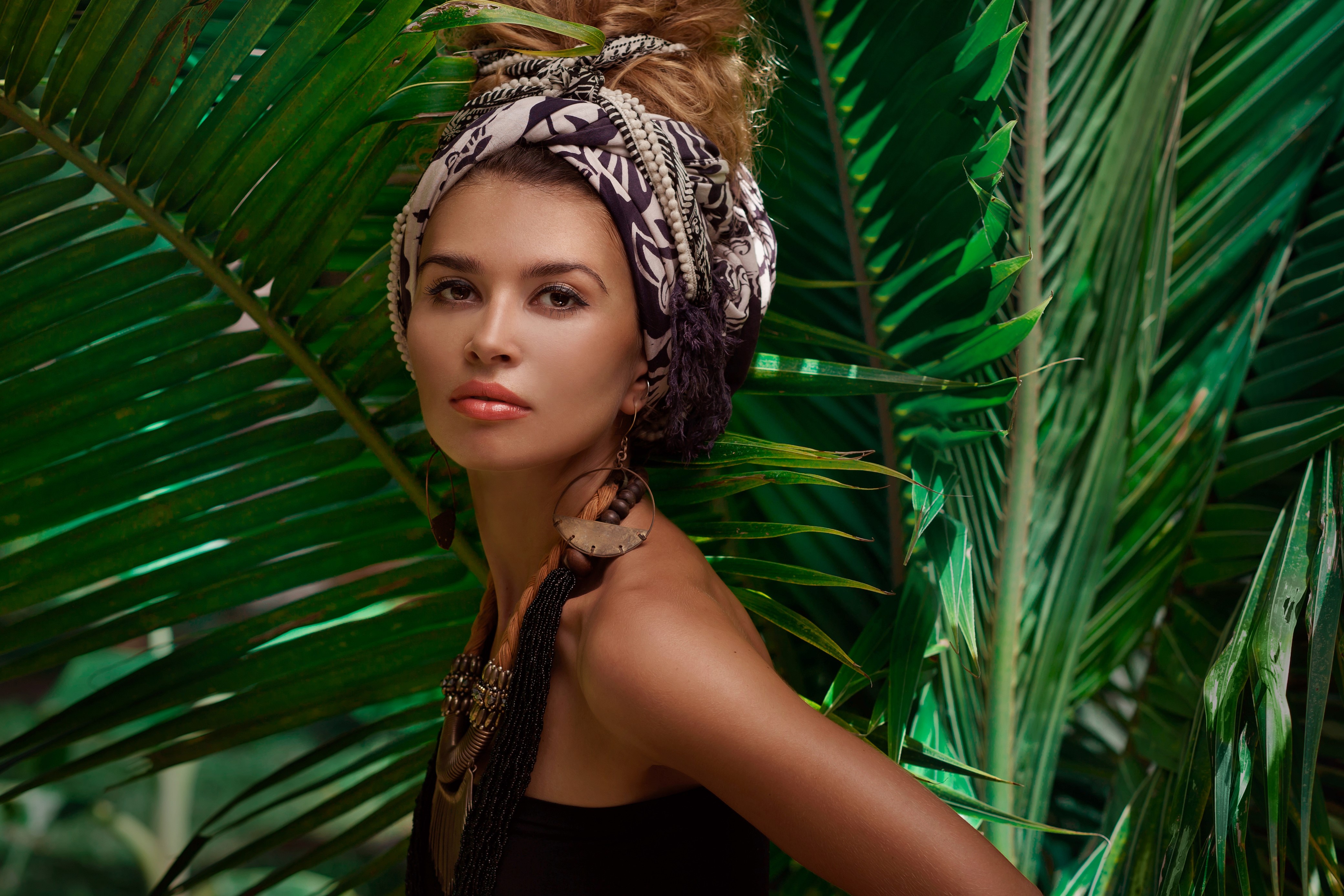 Woman with headscarf and earrings in palm leaves HD Wallpaper
