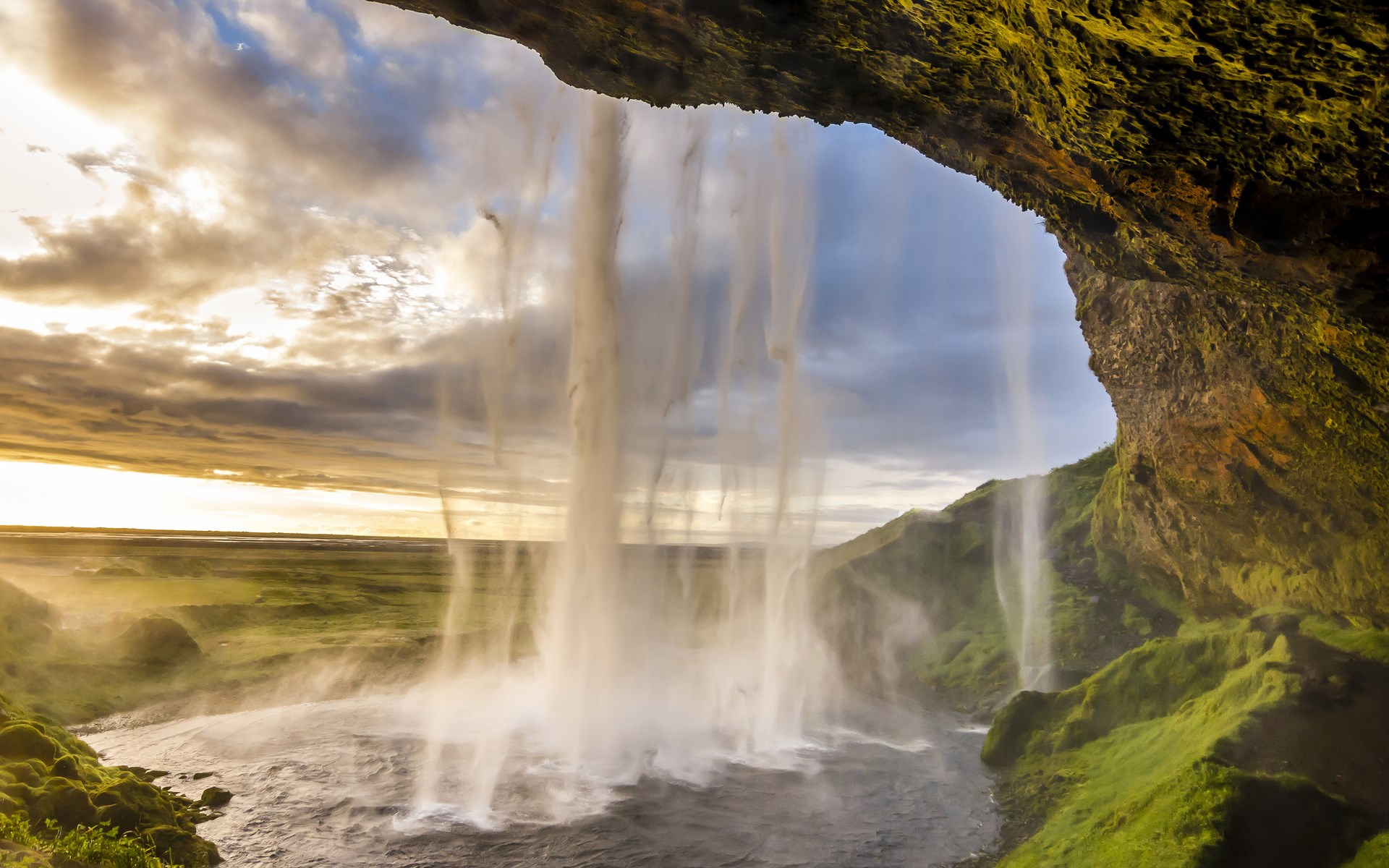 View from behind a waterfall at sunset HD Wallpaper