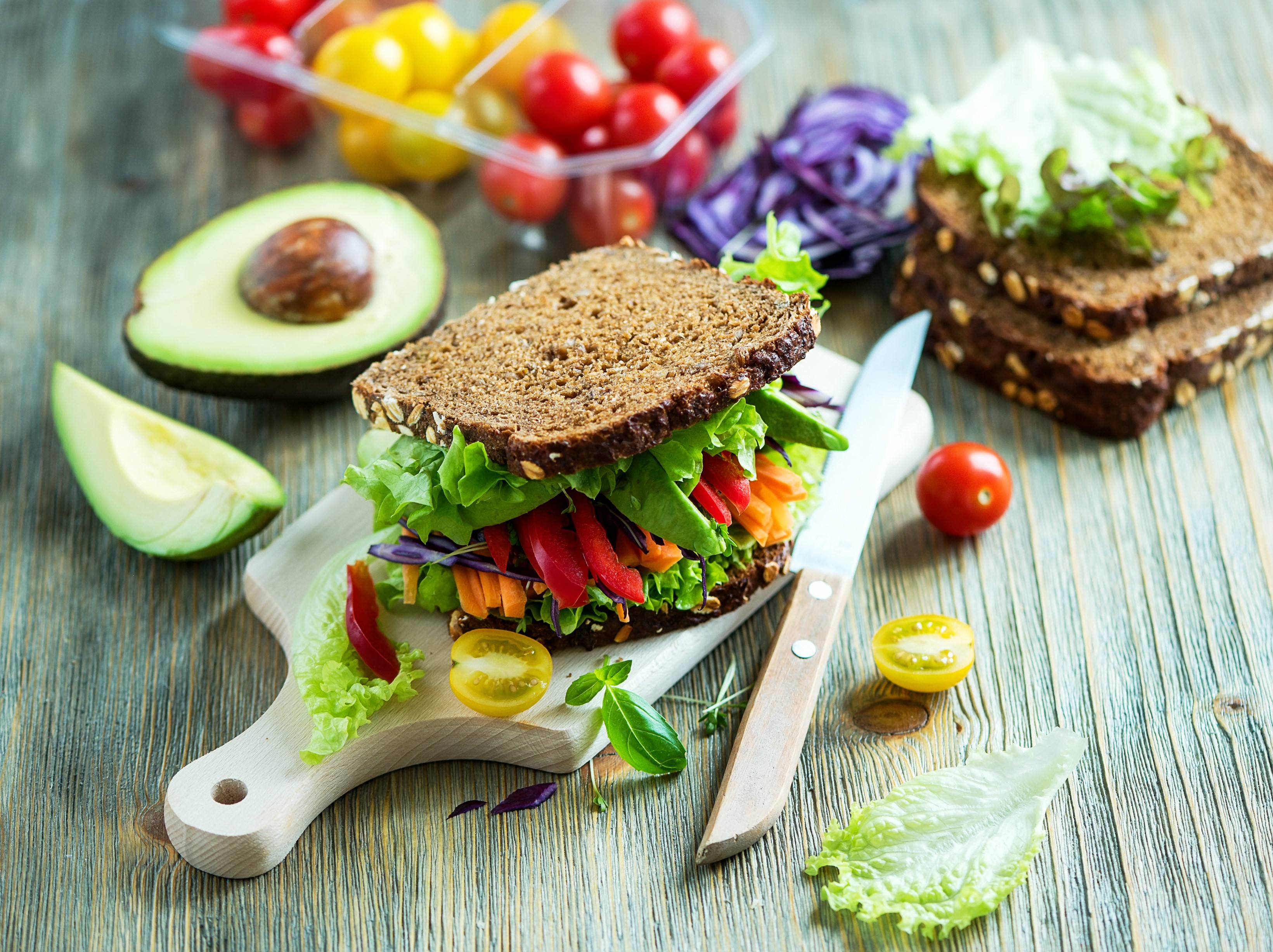 Vegetable sandwich with avocado and cherry tomatoes on a cutting board HD Wallpaper