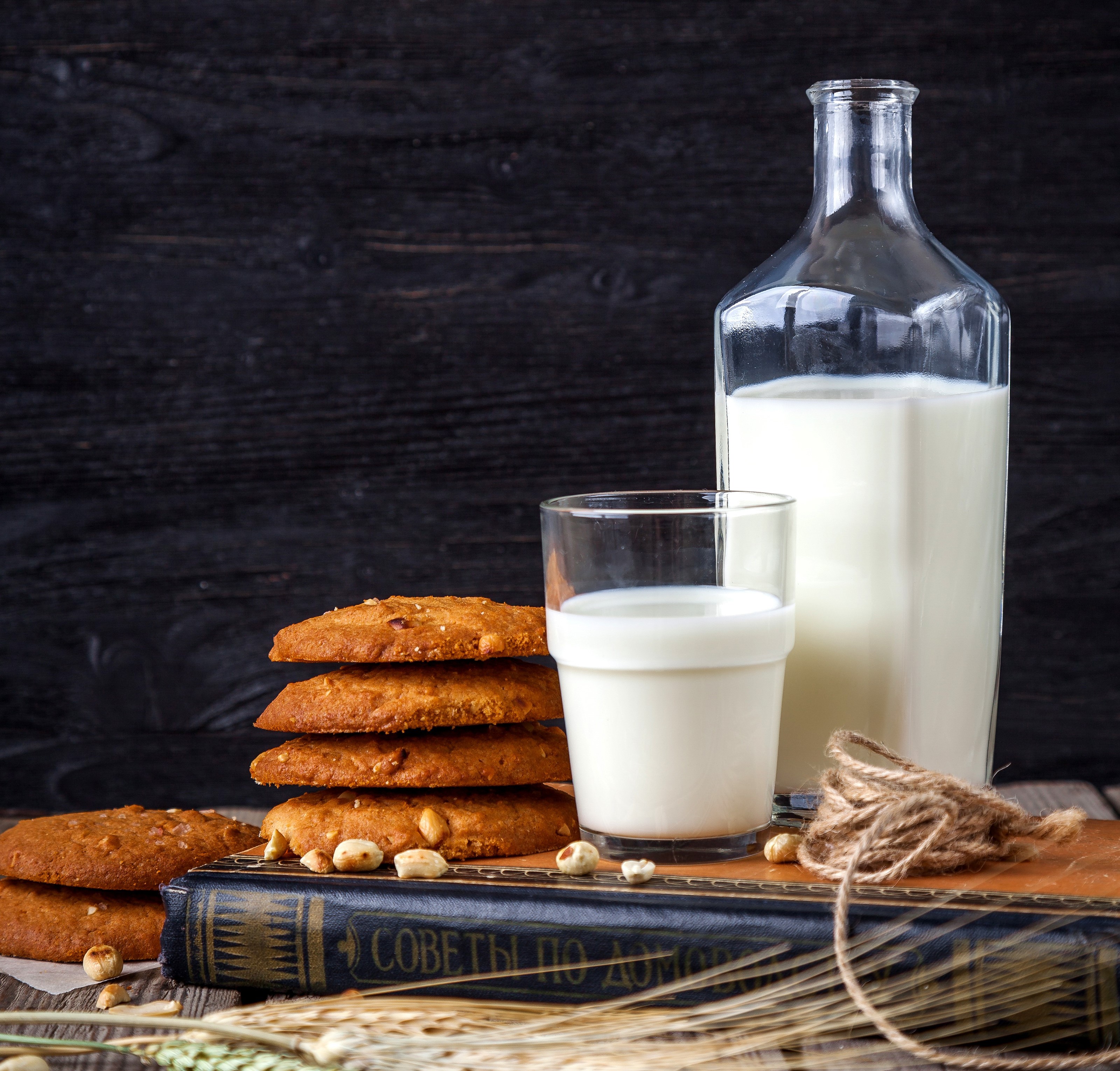 Milk bottle, glass, cookies, and book on wooden table HD Wallpaper