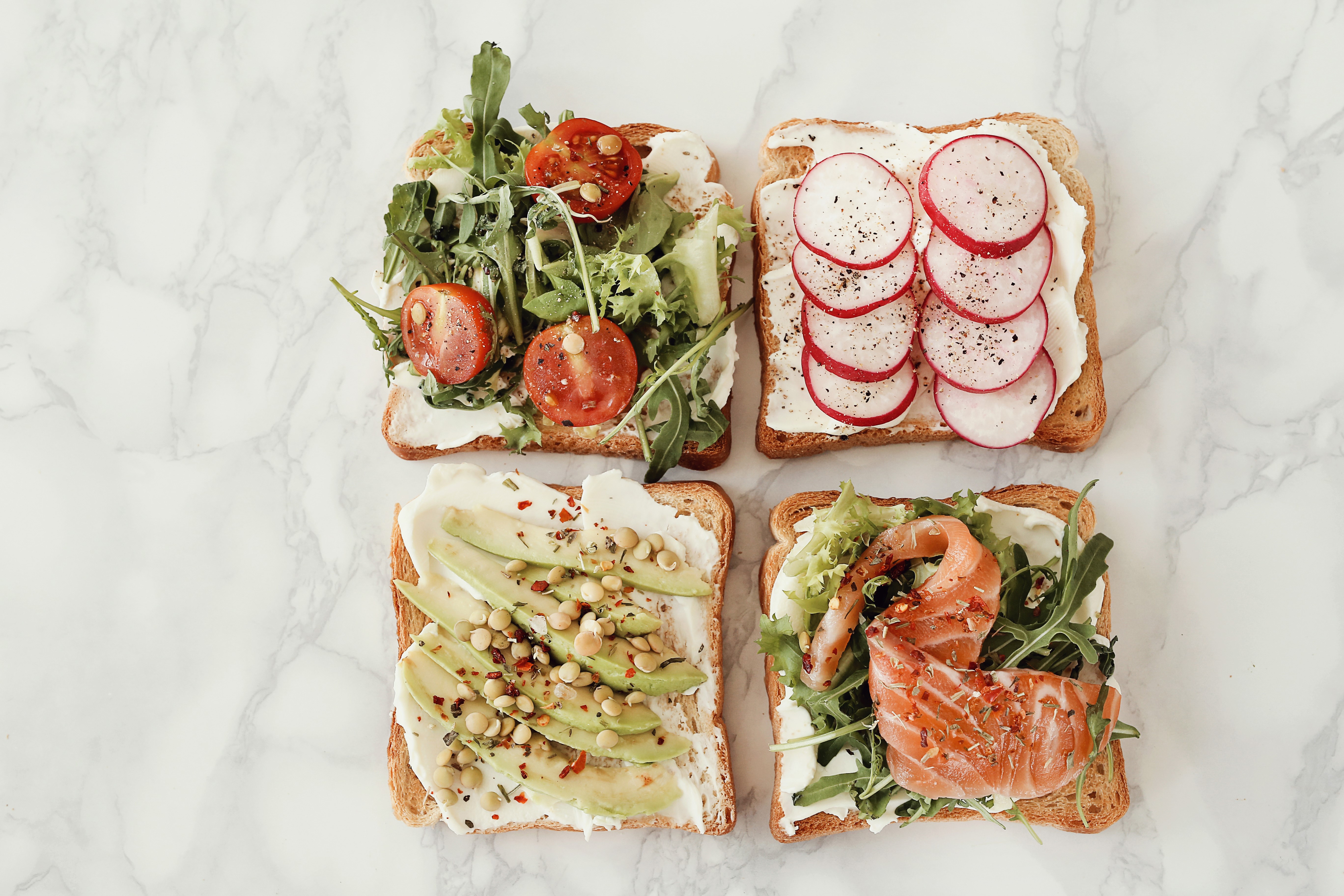 Four open-faced sandwiches with various toppings HD Wallpaper