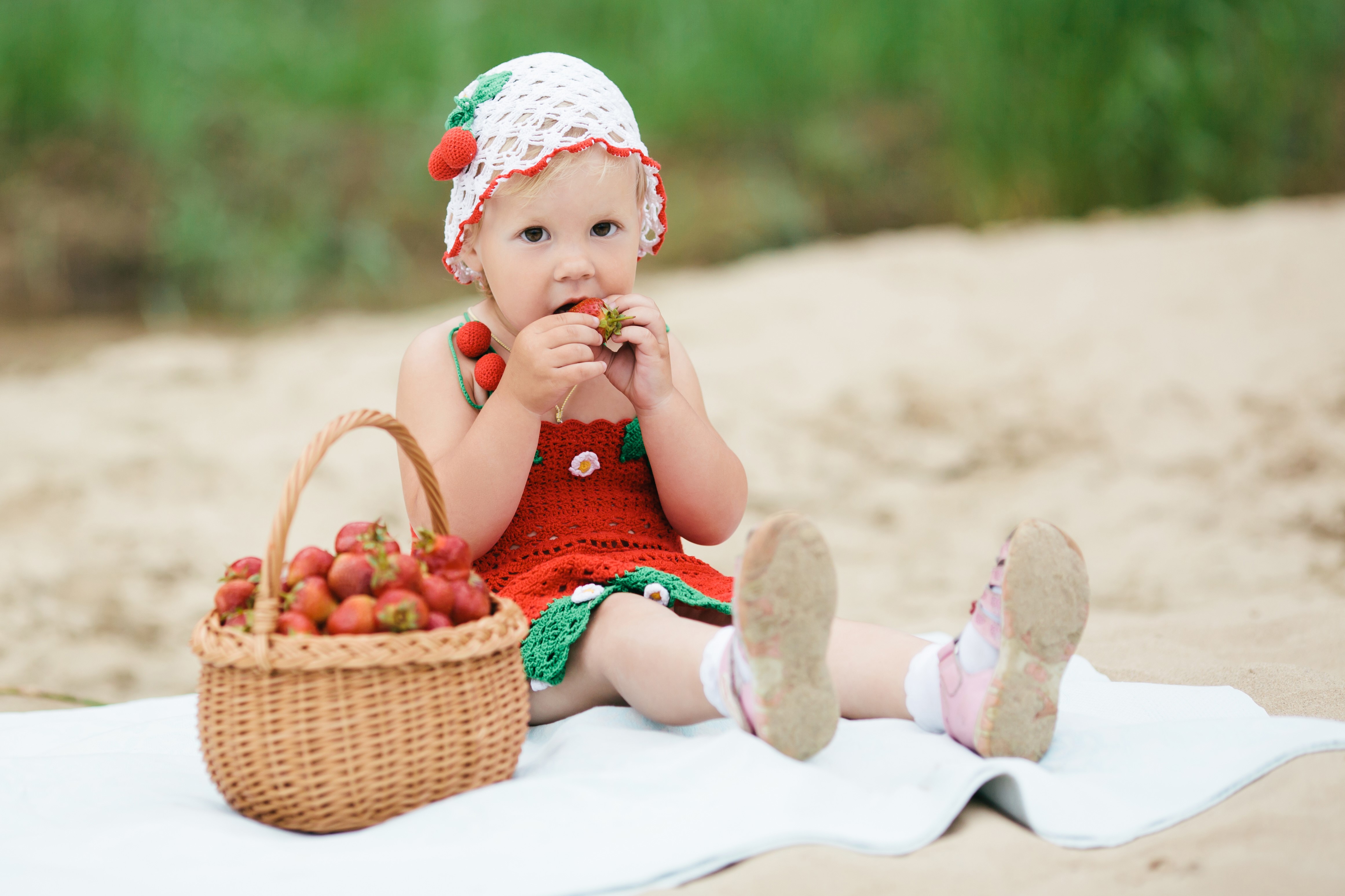 Little girl in strawberry dress eating strawberries HD Wallpaper
