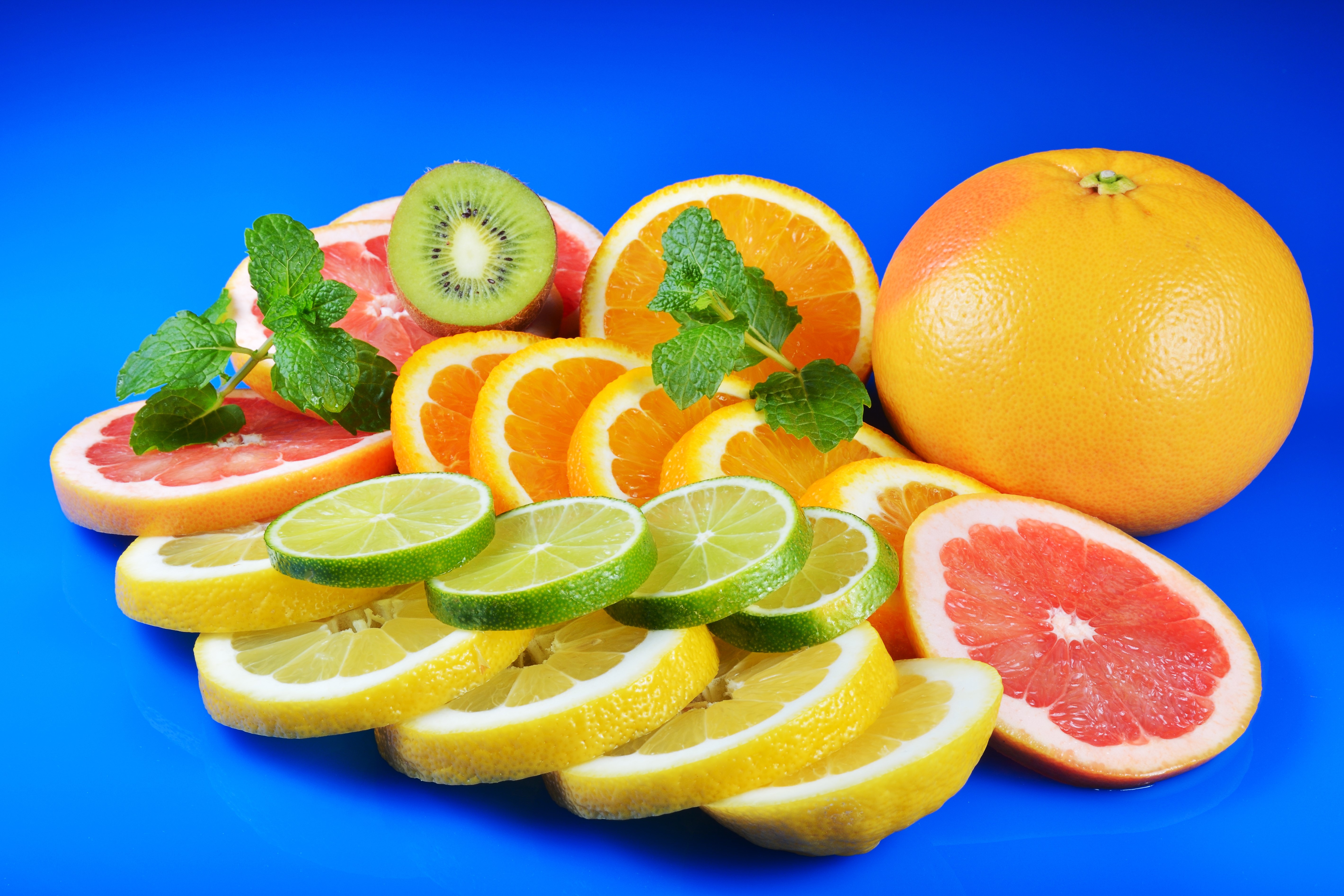 Citrus fruits and kiwi slices on blue background HD Wallpaper