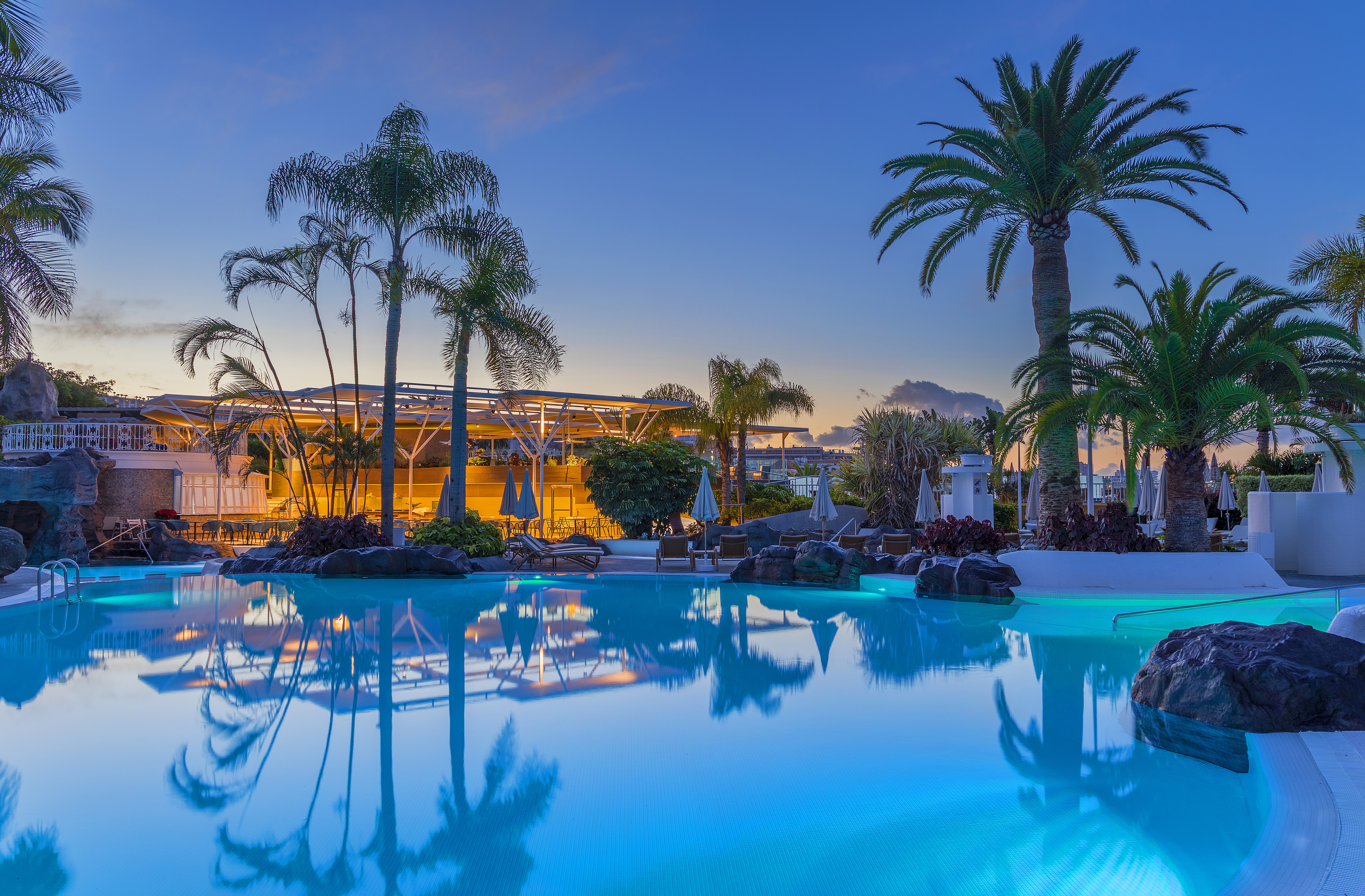 Resort pool with palm trees at dusk in Canary Islands HD Wallpaper