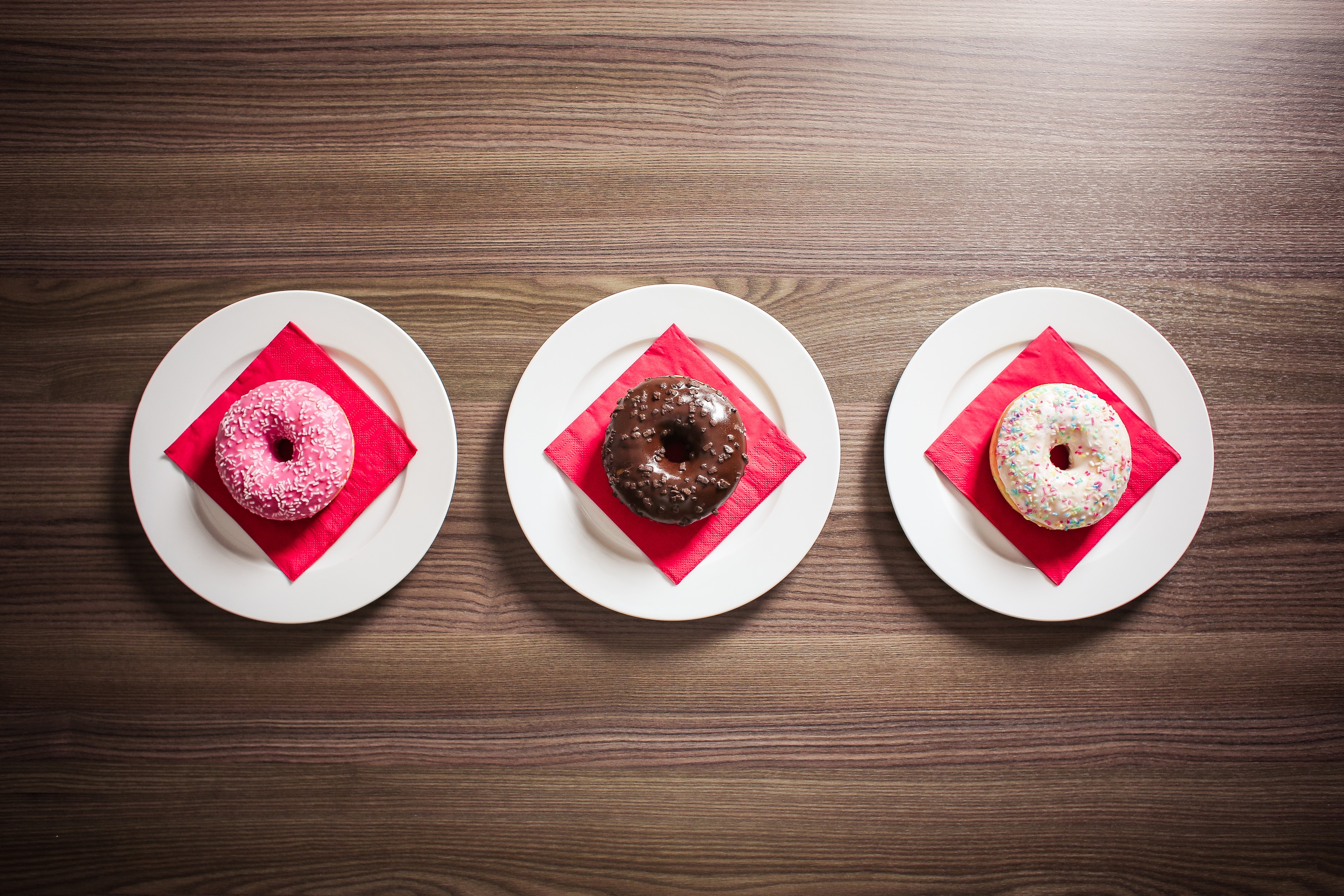 Three donuts on plates with red napkins HD Wallpaper