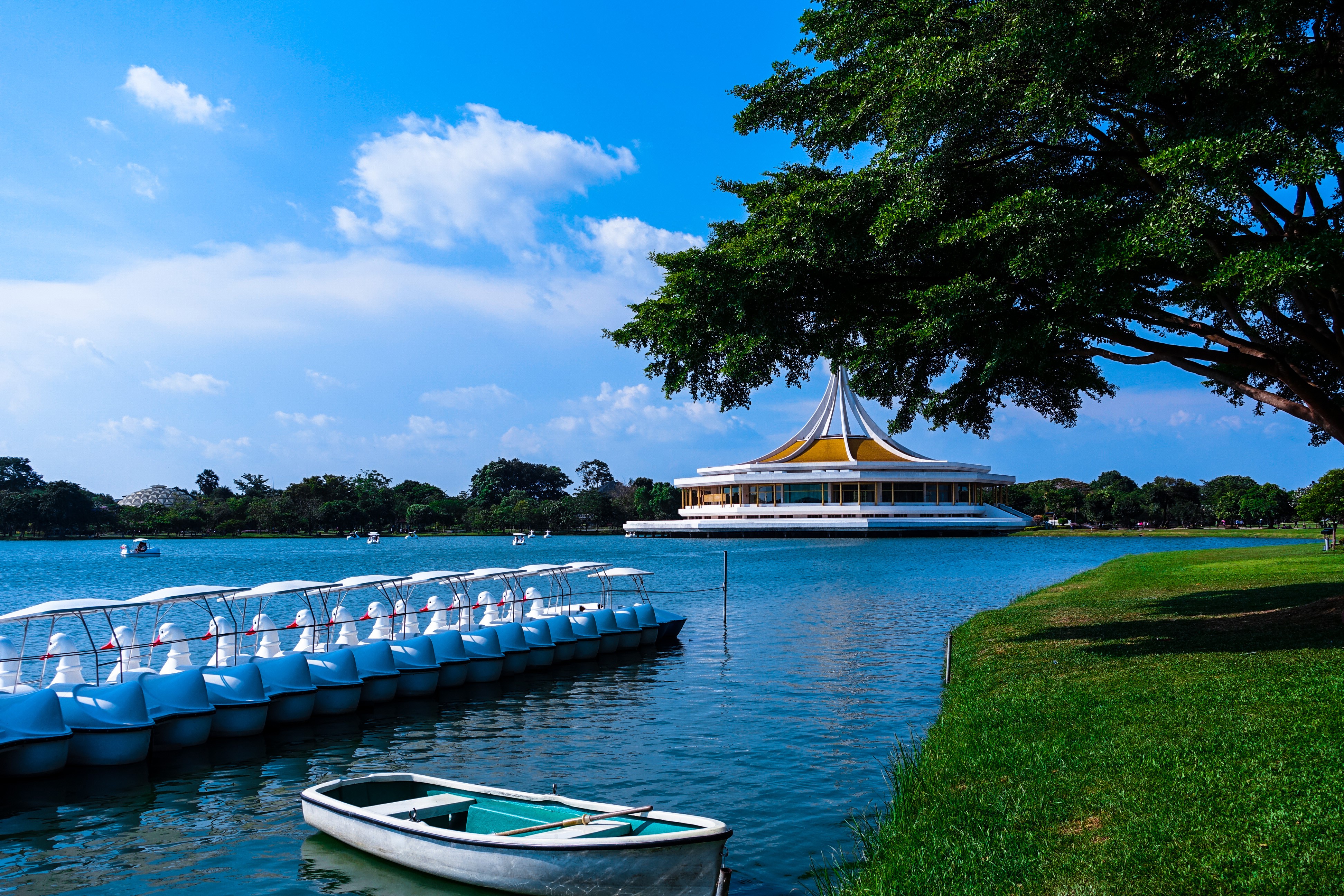 Park with lake, boats, and building in Bangkok, Thailand HD Wallpaper