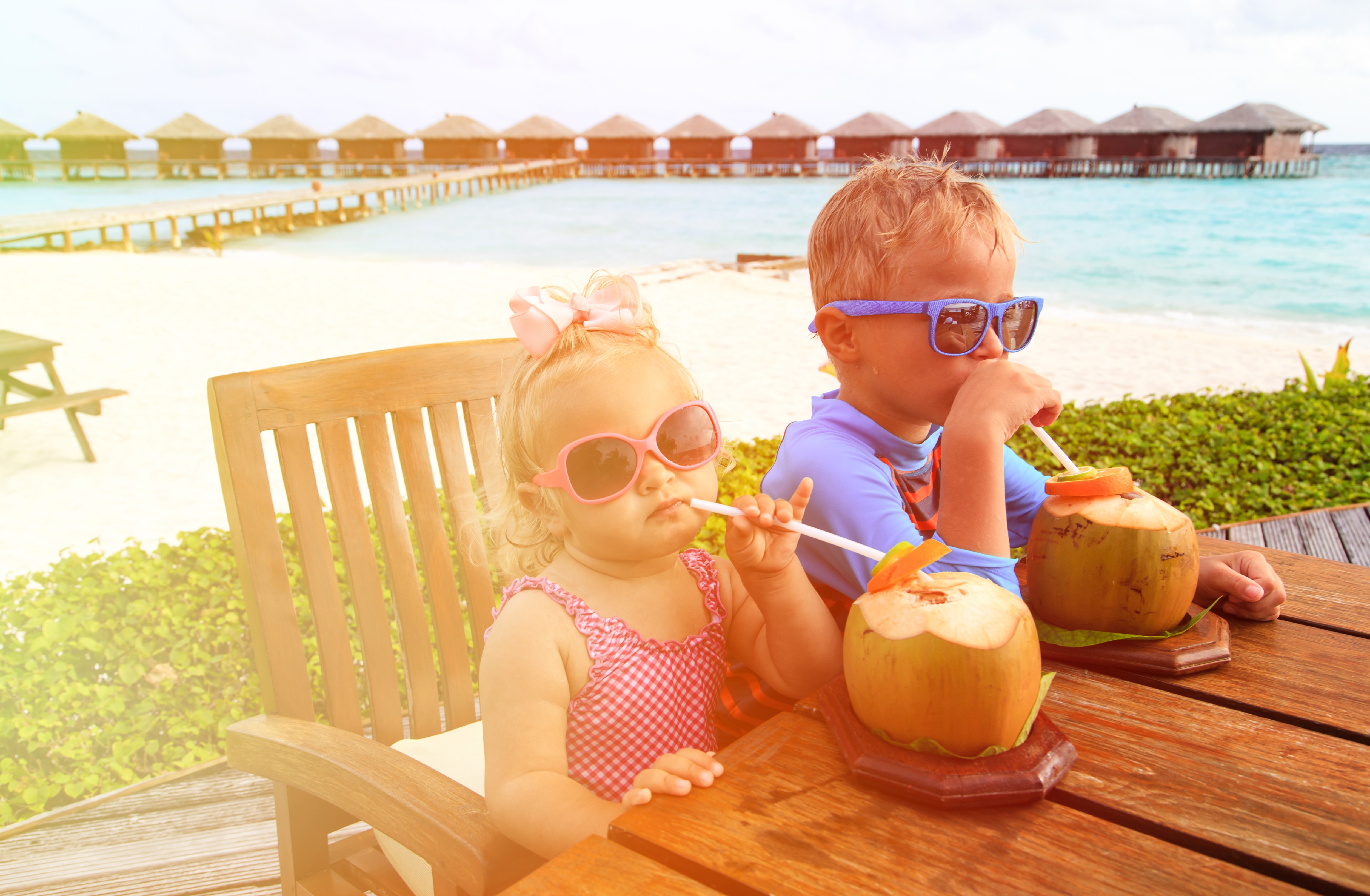 Two children drinking coconuts at a resort HD Wallpaper