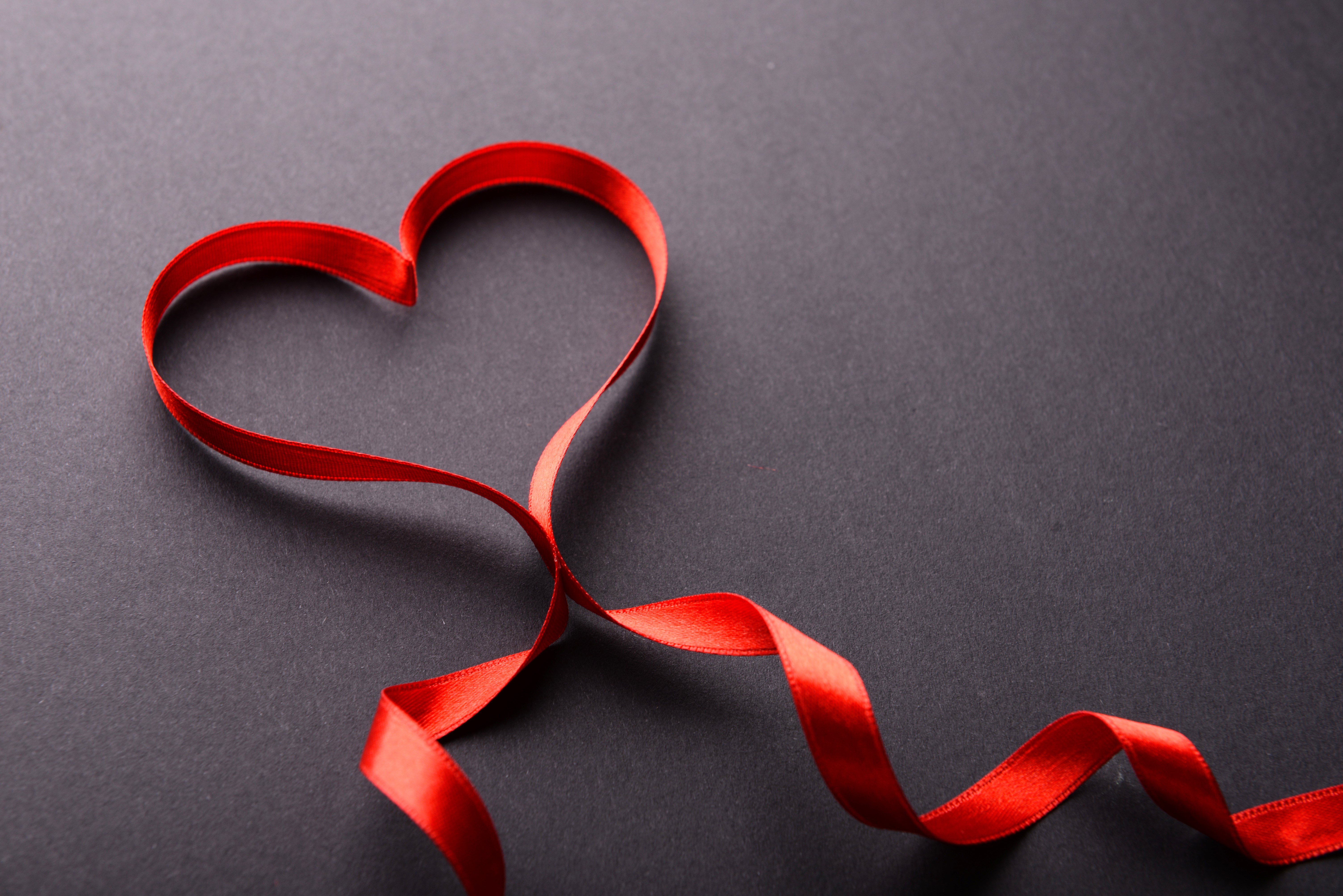 Red ribbon in heart shape on dark background HD Wallpaper