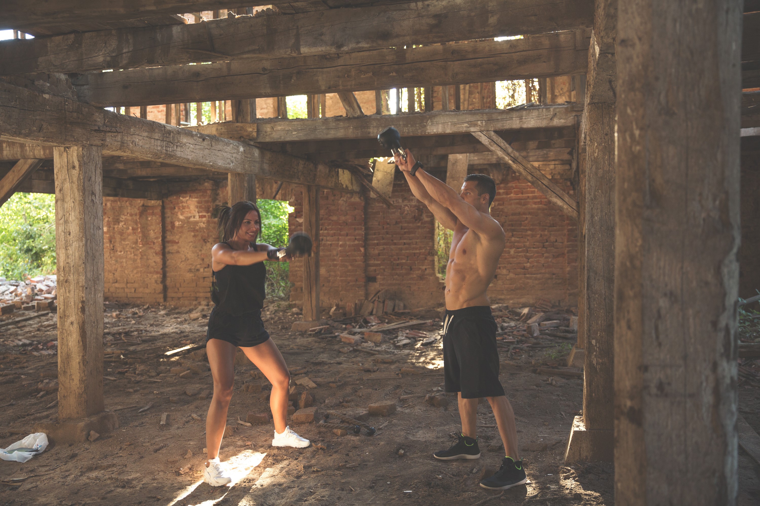 Man and woman doing kettlebell workout in abandoned building HD Wallpaper
