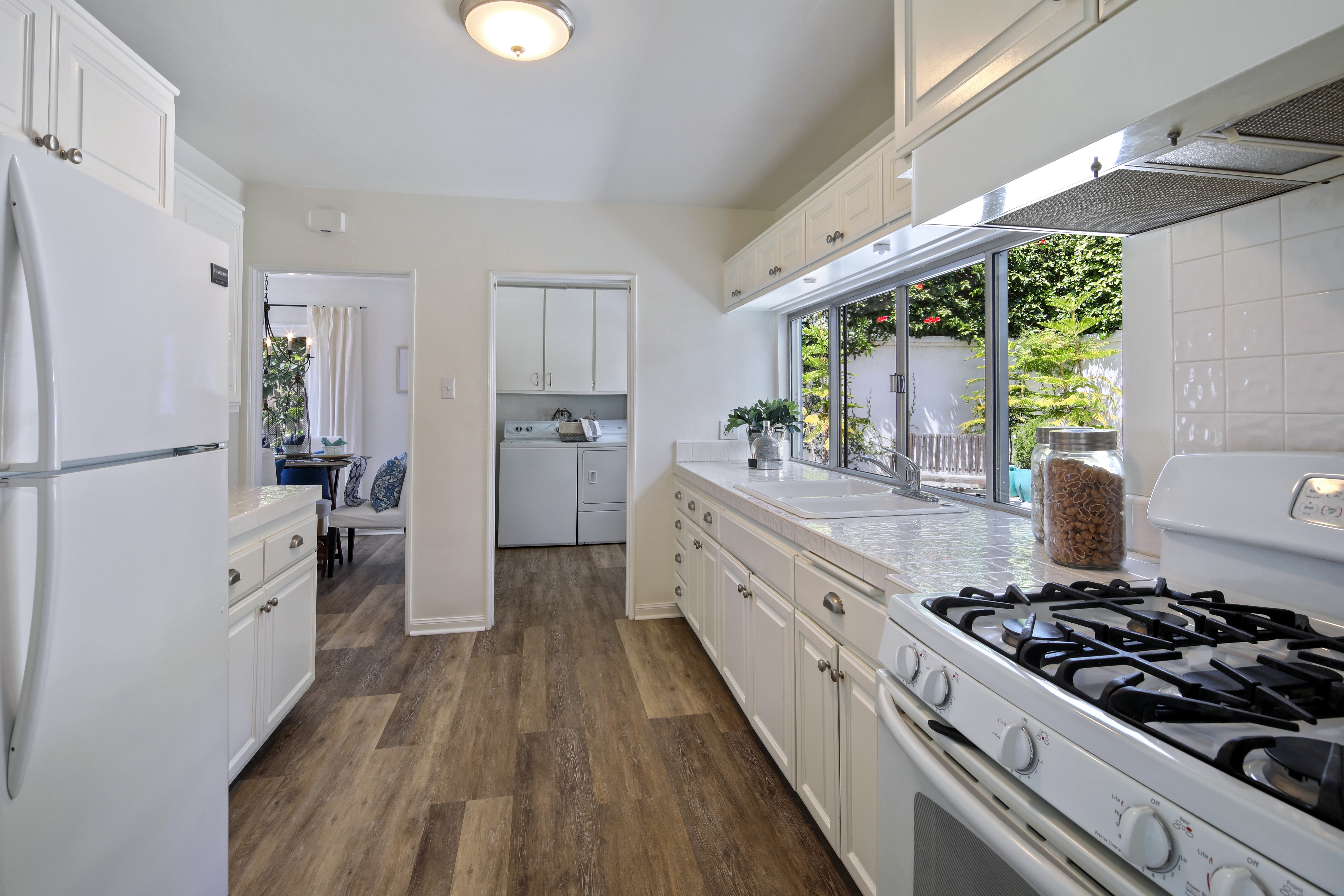 Kitchen with white cabinets, appliances, and window view HD Wallpaper
