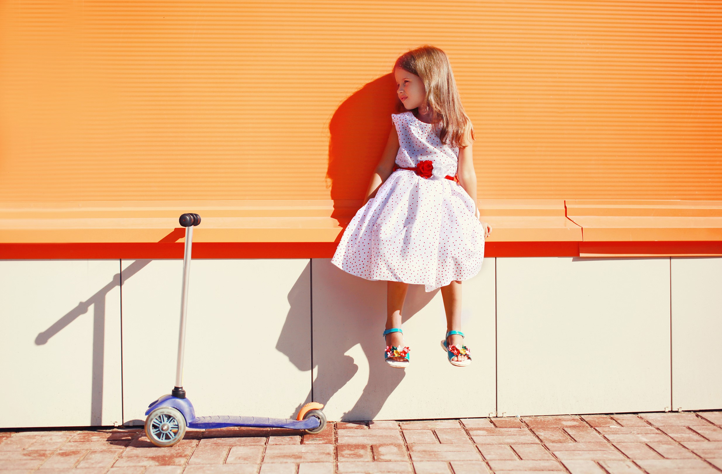 Girl in polka dot dress sitting on bench with scooter HD Wallpaper