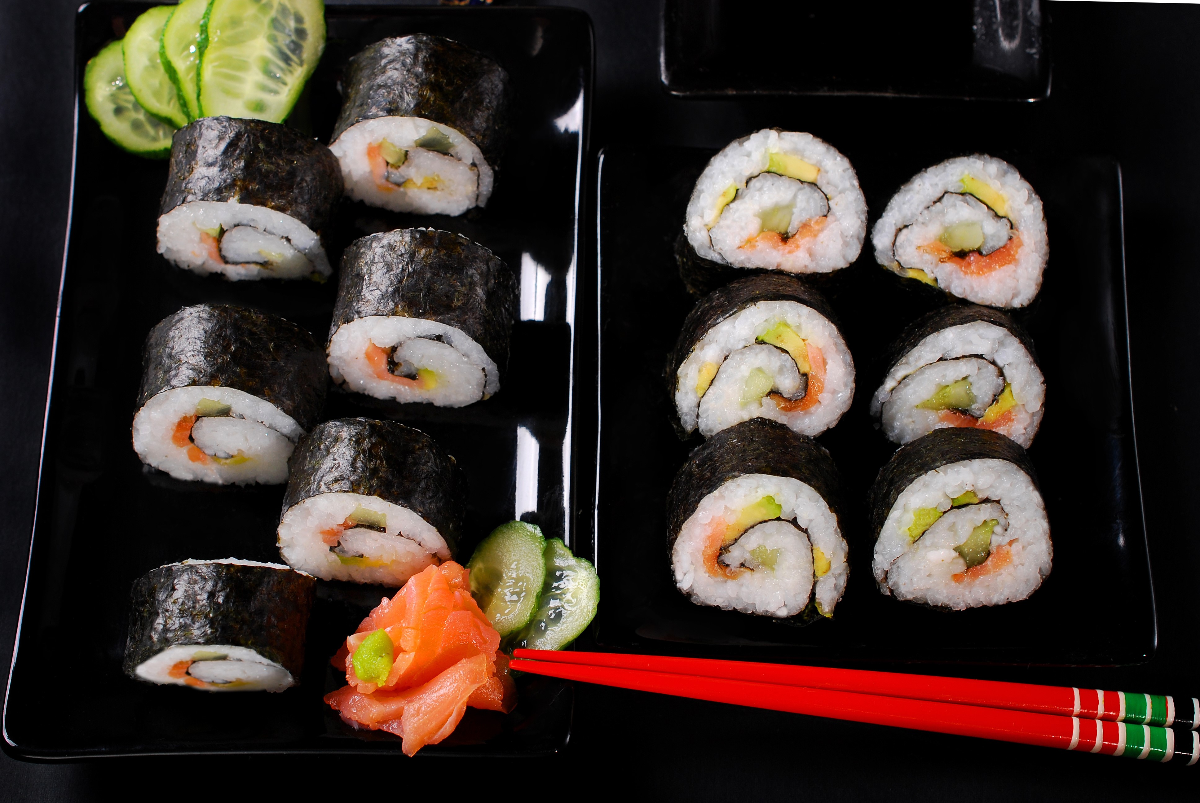 Sushi rolls with salmon and cucumber on black plates HD Wallpaper