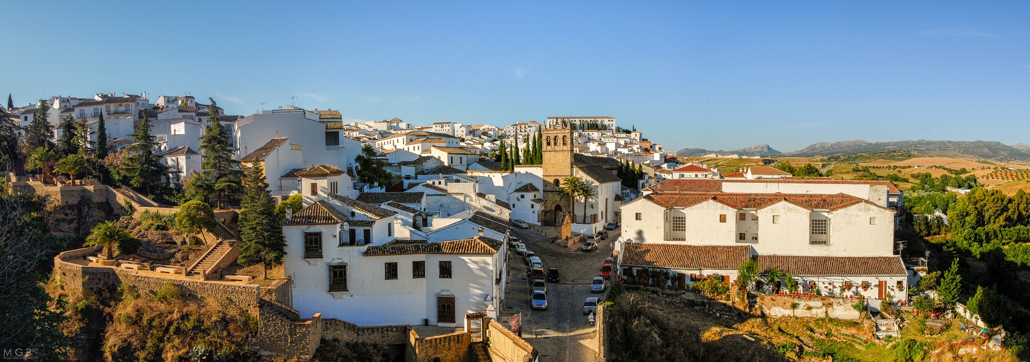 Panoramic view of Ronda, Spain with white houses and a church tower HD Wallpaper